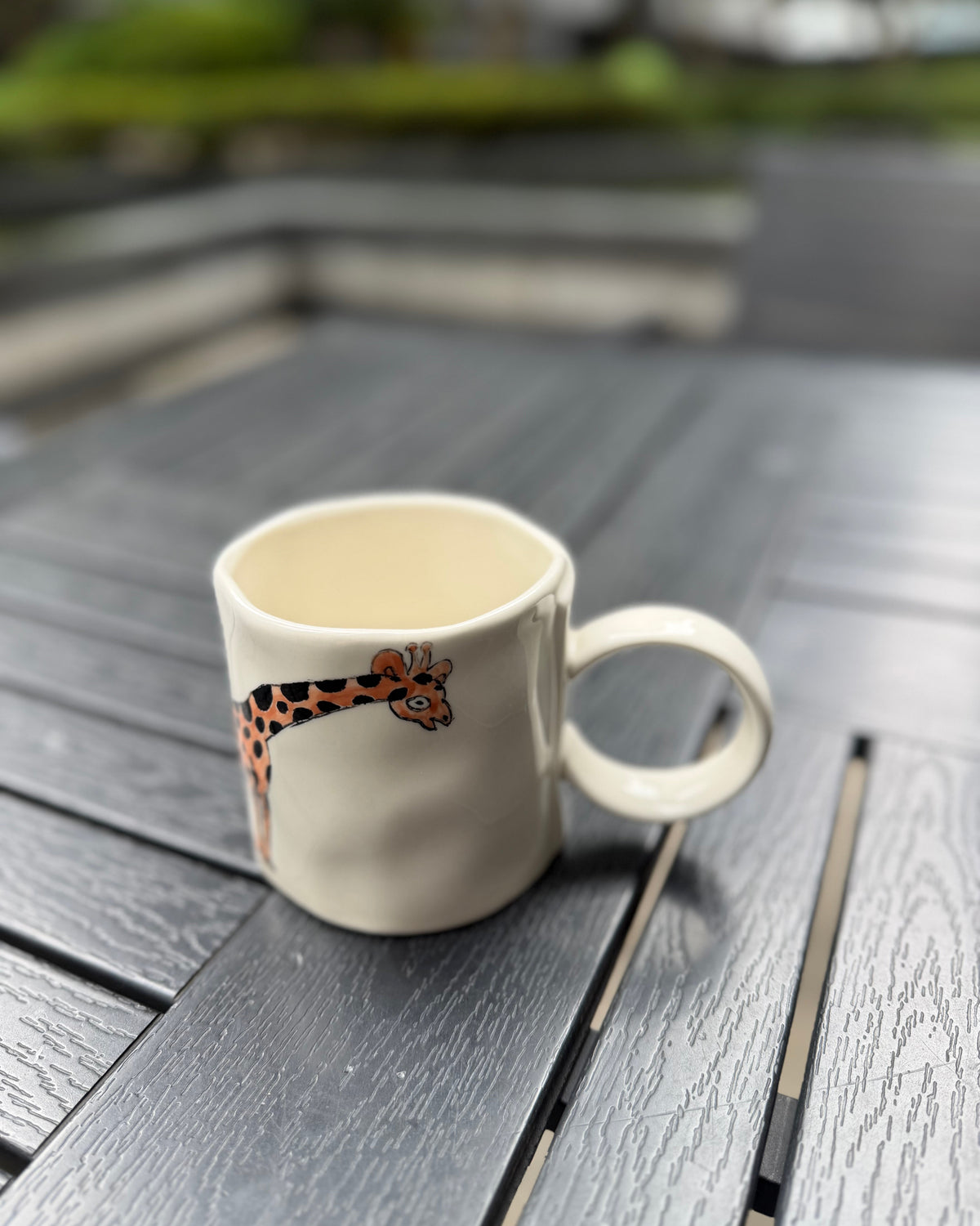 Gentle Giraffe ceramic mug side angle view, hand-painted stoneware with giraffe peeking over the rim, The Quiet Clay