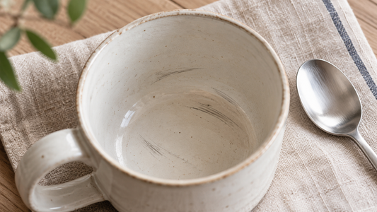 Grey metal utensil marks inside a light-colored ceramic mug
