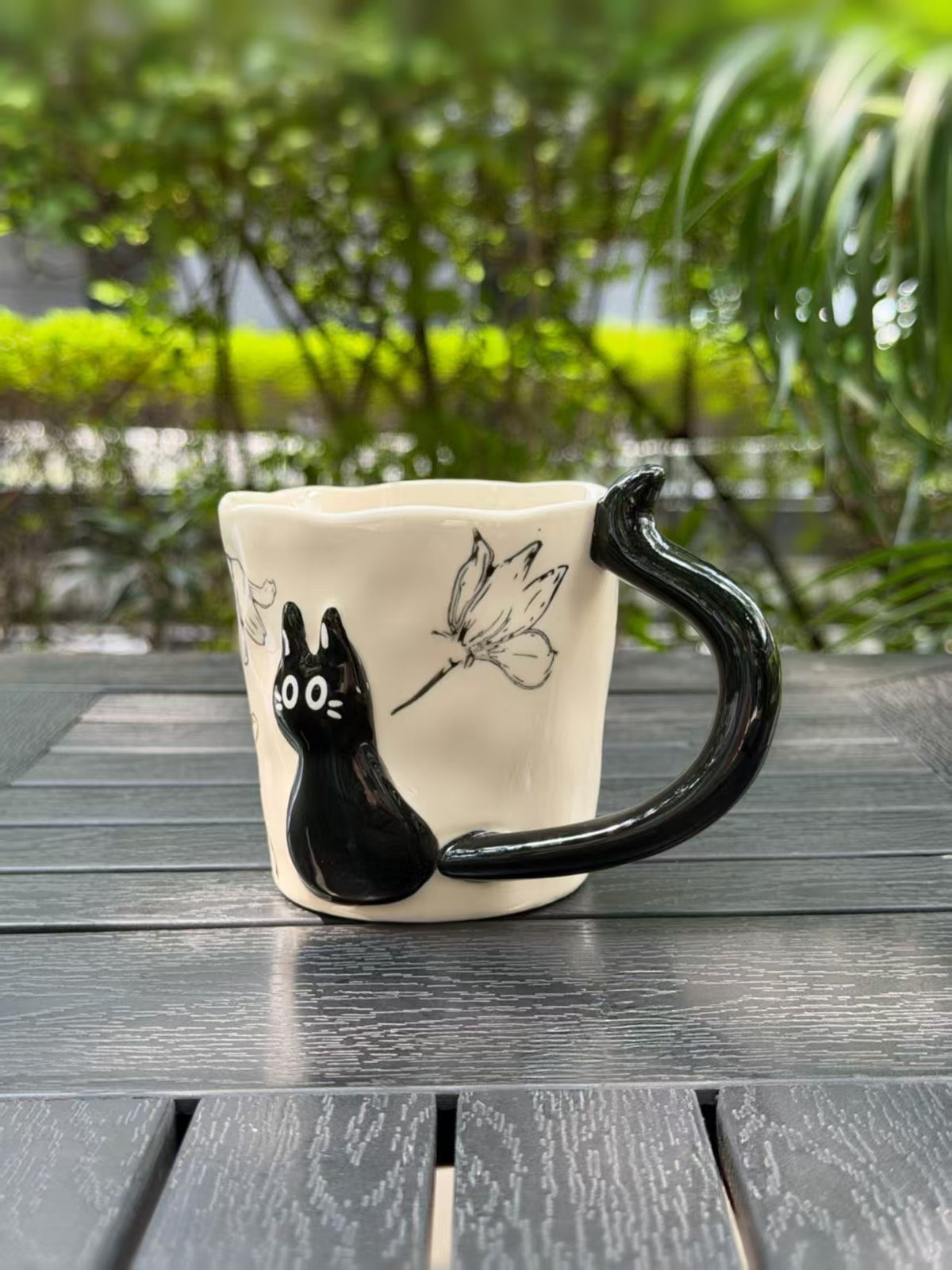 Angled side view showing the raised black cat beside the curved handle