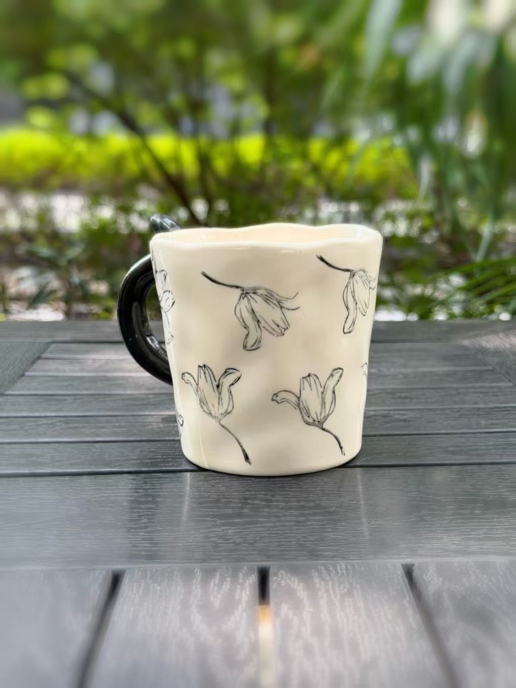 Side view of the cream floral mug showing its black handle and gently shaped rim