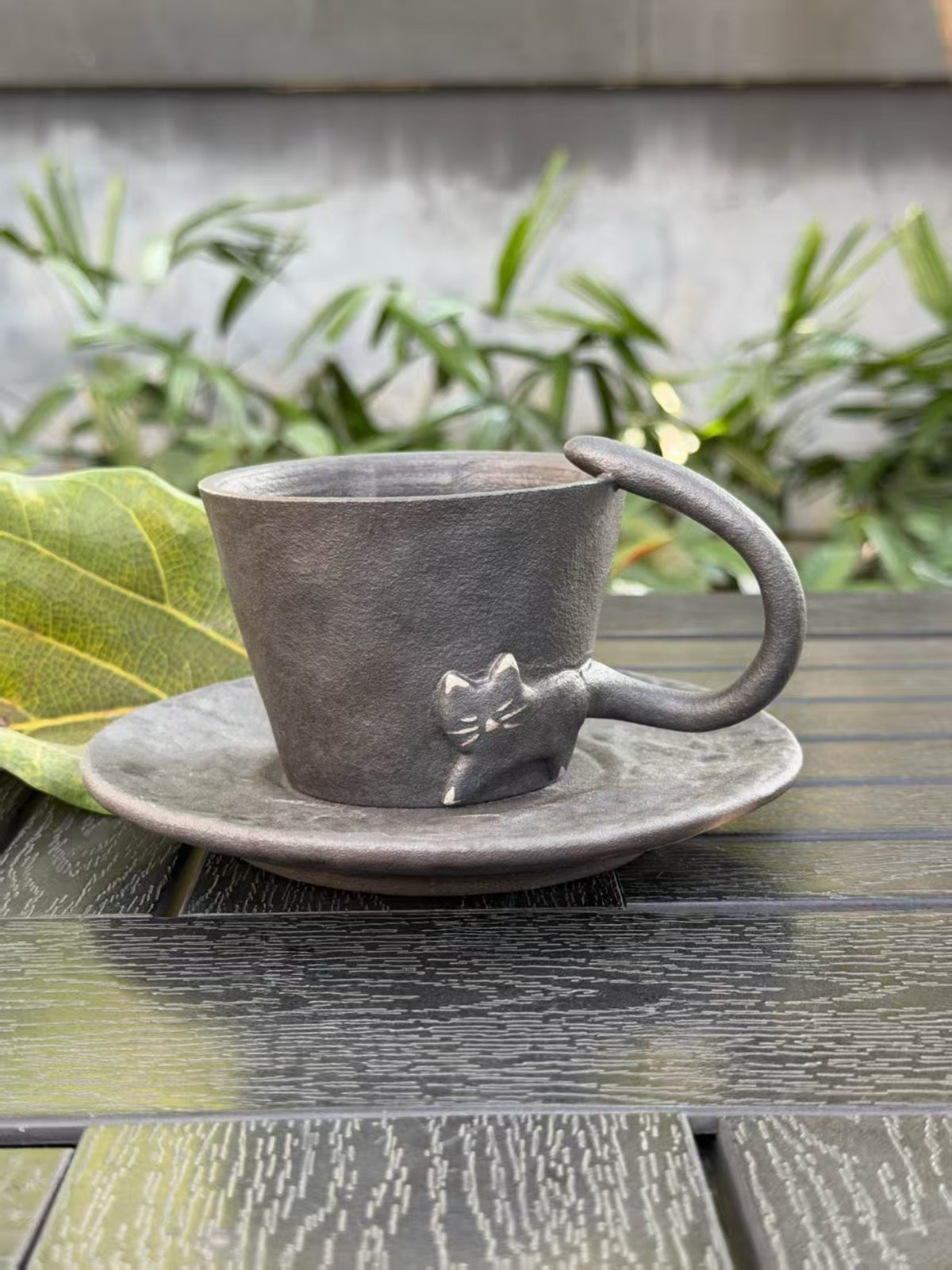 Black cat ceramic cup with matching dark saucer and sculptural tail handle