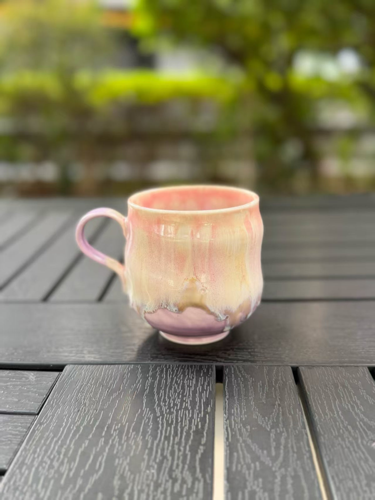 Back of the pink and lavender ceramic mug, with an uneven flowing glaze edge above the purple base.