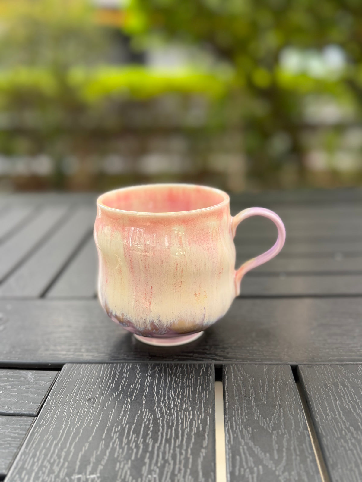 Slightly elevated front view of the mug showing its pink interior rim, cream-colored body and curved handle.