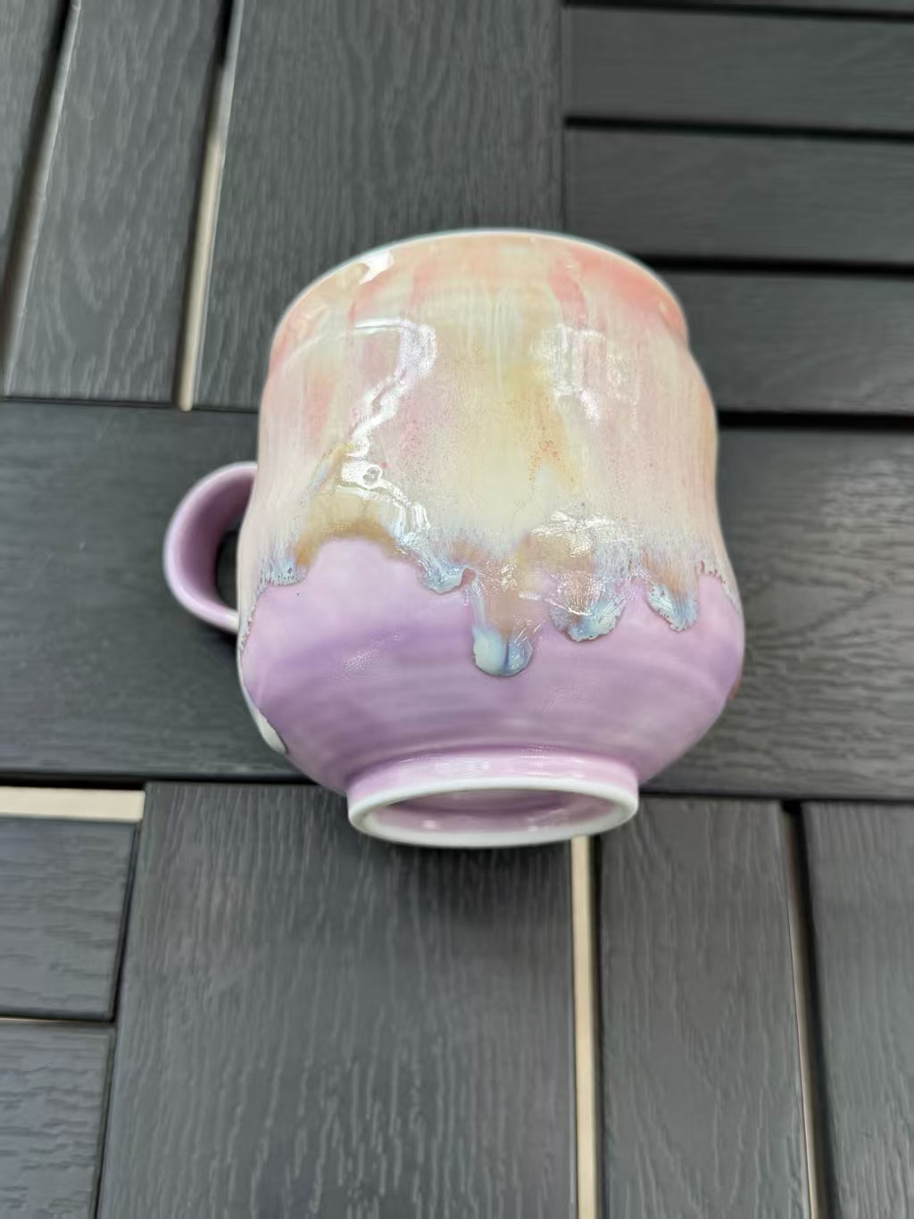 Close view of cream glaze dripping over the lavender lower half of the mug, with its foot ring visible.