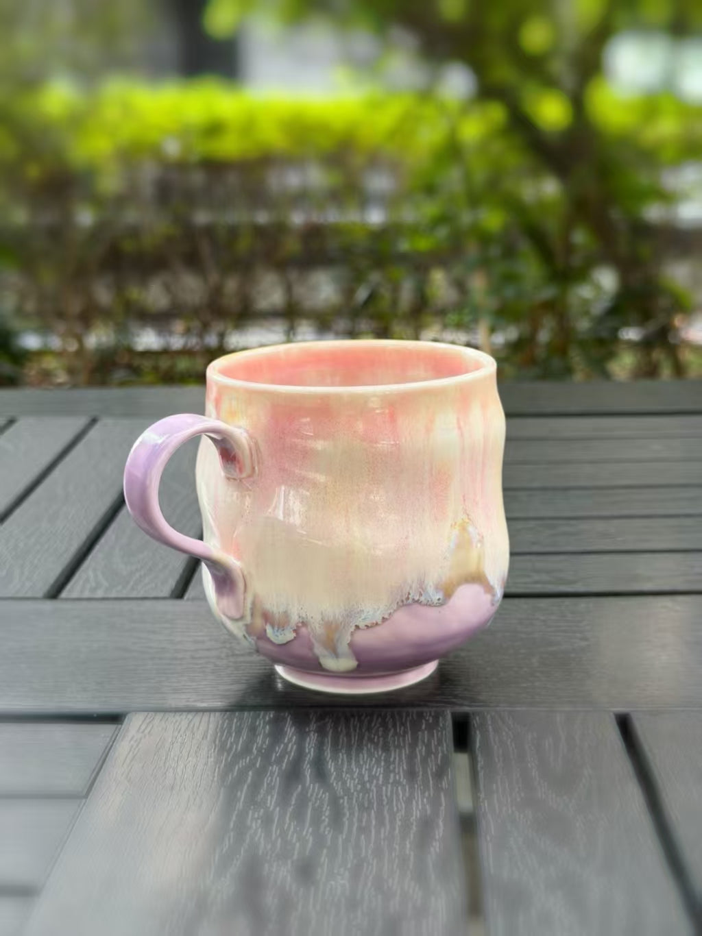 Left-side angled view of the ceramic mug showing its lavender handle and flowing glaze near the base.