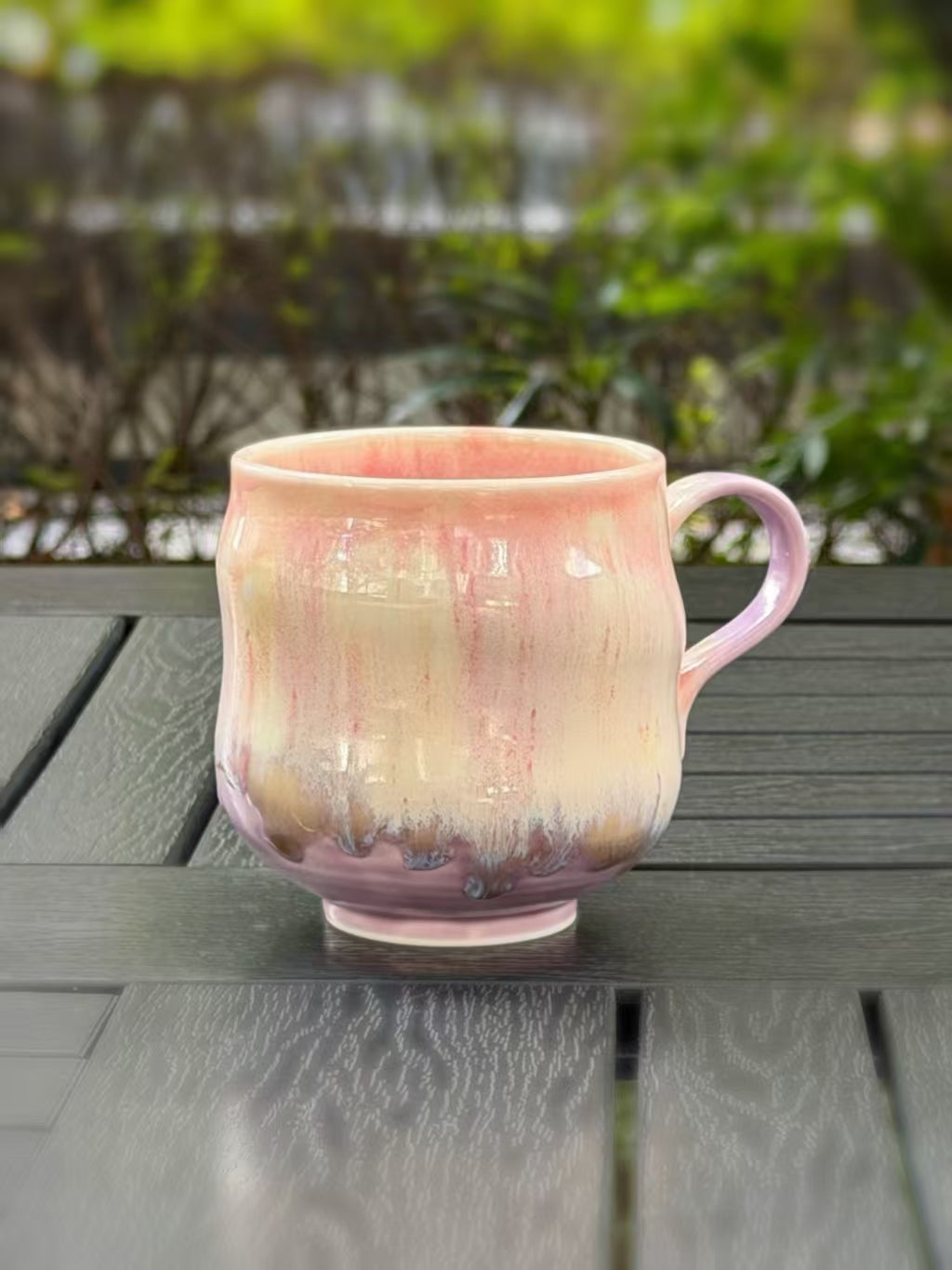Right-handle view of the kiln-glazed mug, showing fine pink streaks and a lavender glaze around the base.