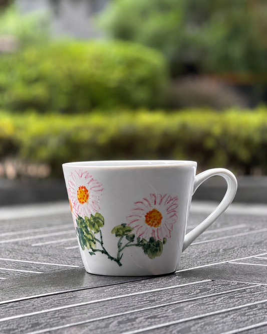 Blushing Daisy Hand-Painted Ceramic Mug – front view showing two pink daisy blooms with green leaves, The Quiet Clay