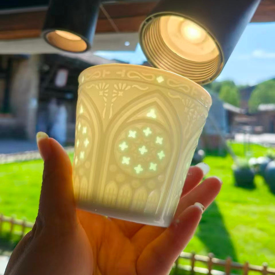 Backlit Linglong porcelain cup showing the translucency of its hand-carved openwork pattern