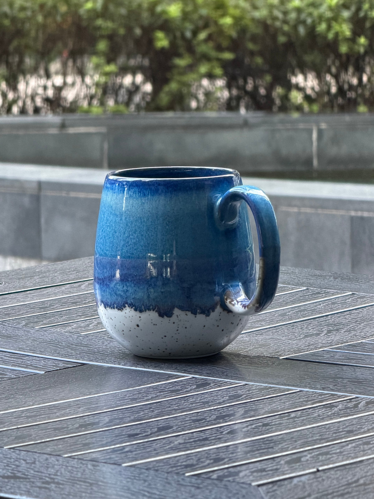 Side view of the 800 ml Coastal Tide mug showing its rounded form, curved handle and layered blue reactive glaze