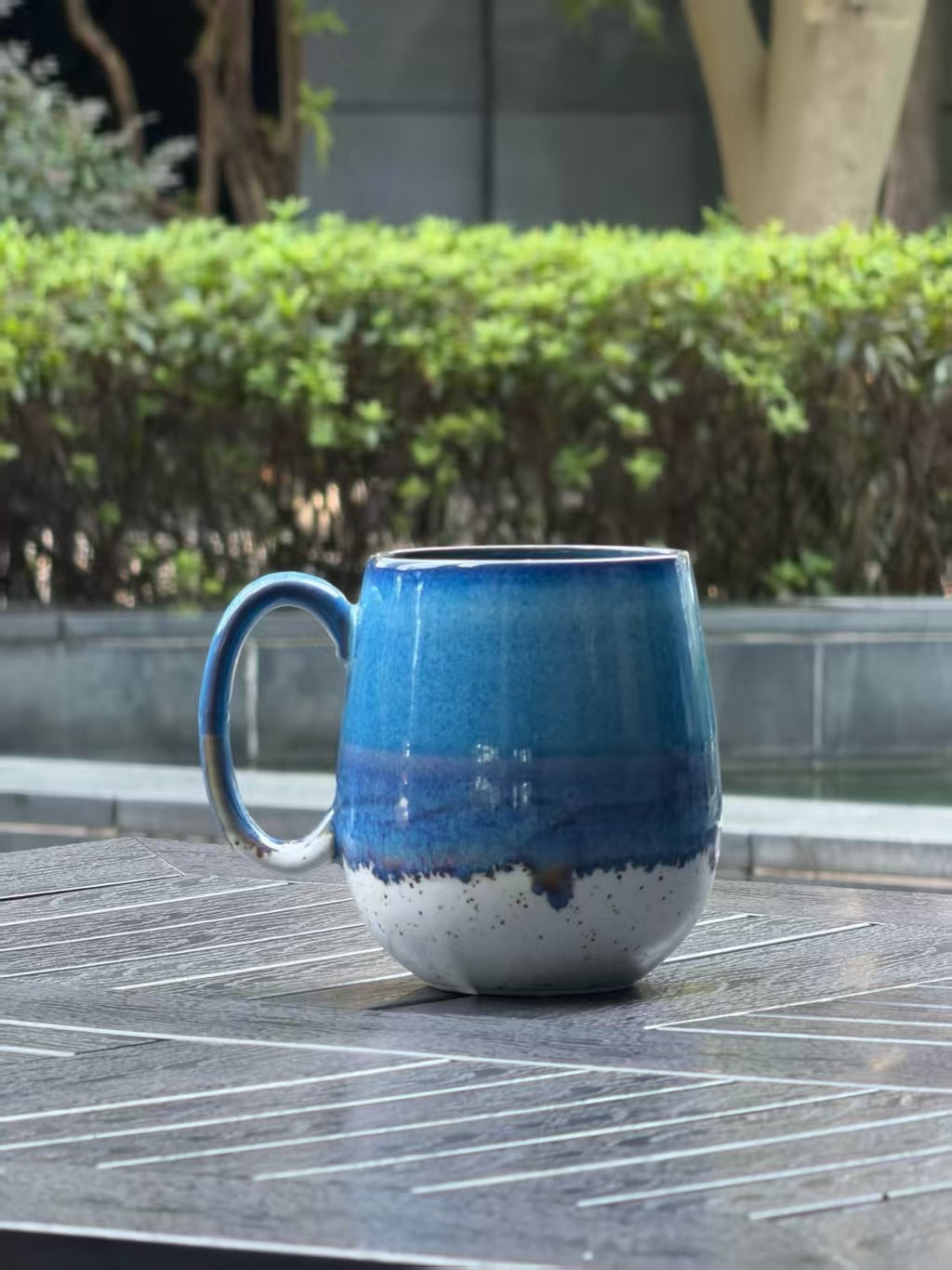 Back view of the one-of-a-kind Coastal Tide mug showing natural blue, violet and speckled cream glaze variations