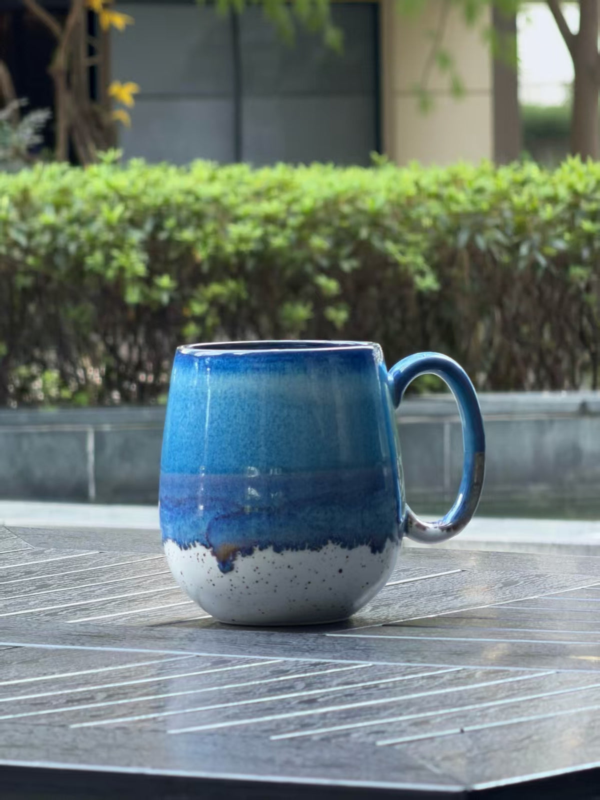 Side view of Coastal Tide oversized reactive glaze mug showing its rounded body, layered blue glaze and curved handle