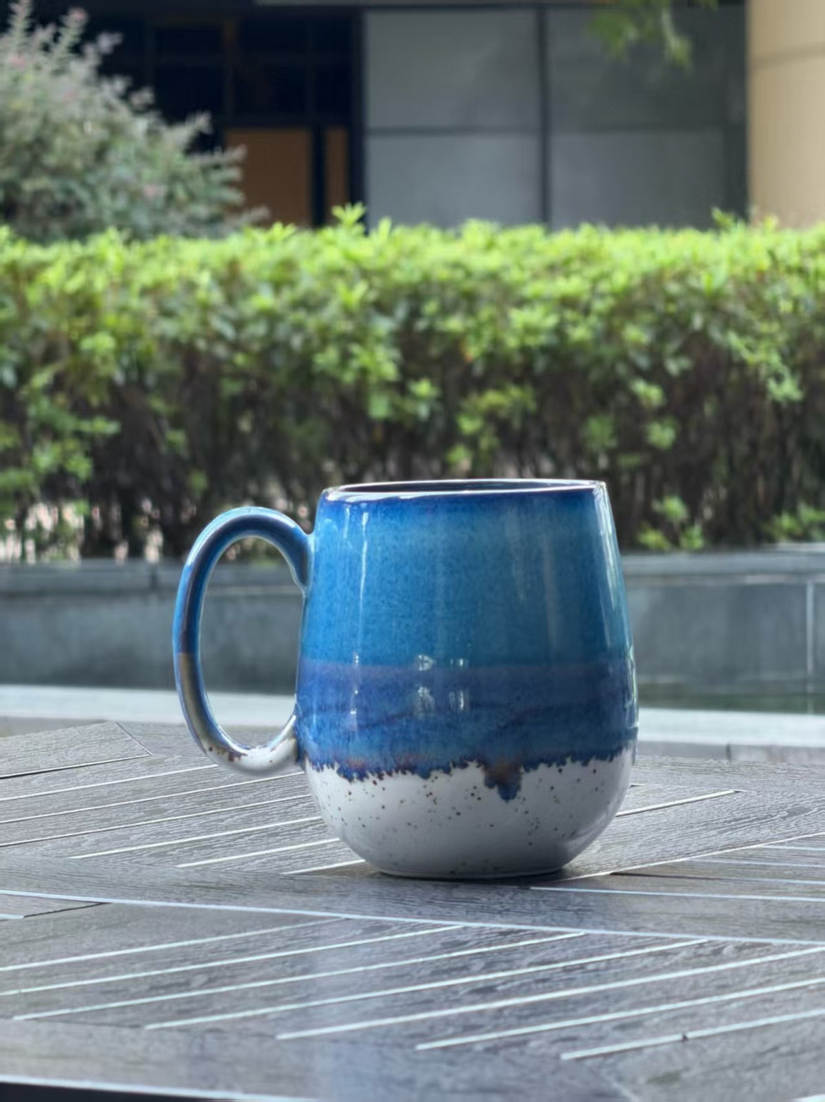 Back view of Coastal Tide mug showing ocean blue and violet reactive glaze over a warm speckled cream base