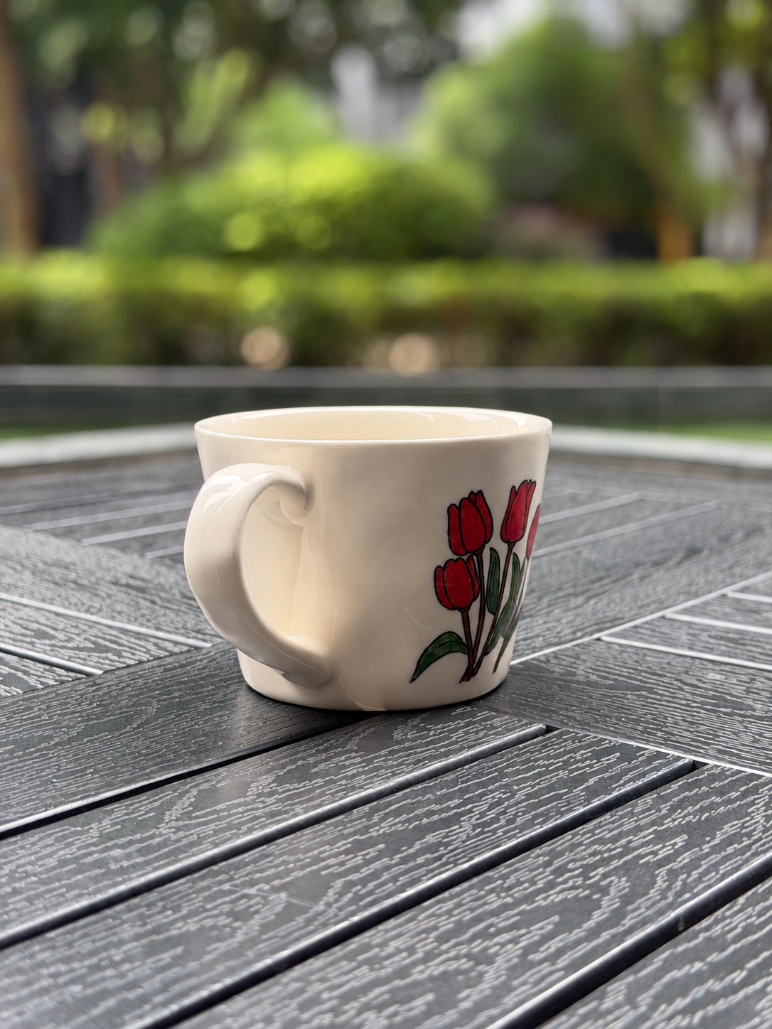 Rear side view of a cream ceramic tulip mug highlighting the curved handle and wraparound floral design
