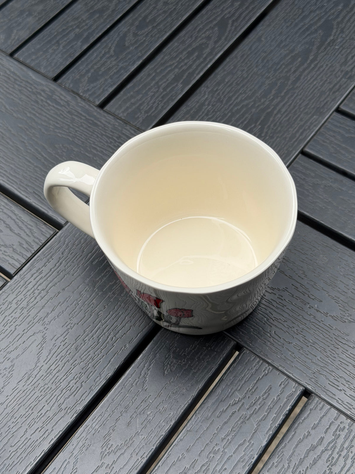 Top-down view of an empty cream ceramic coffee mug showing its smooth glazed interior, wide opening, and curved handle