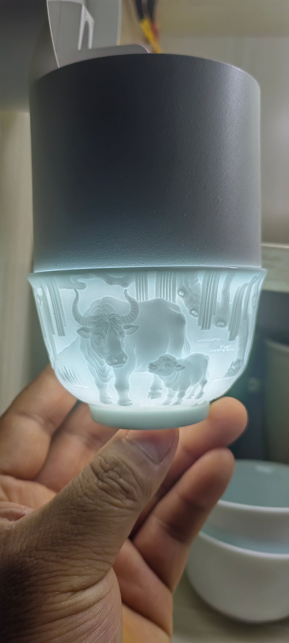 Hand-carved Ox Chinese Zodiac porcelain tea cup by Yan Wenlu illuminated to reveal the detailed relief