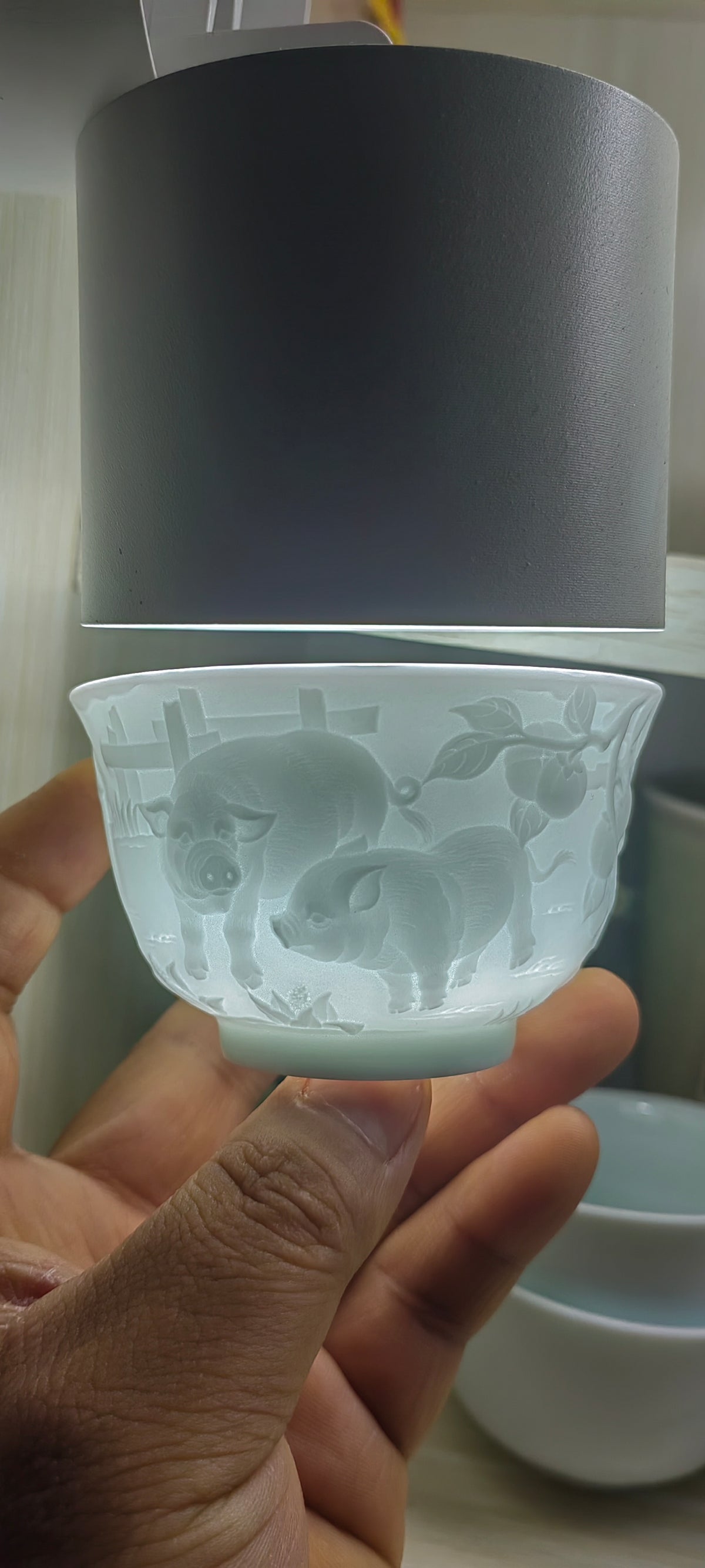 Hand-carved Pig Chinese Zodiac porcelain tea cup by Yan Wenlu illuminated to reveal the sculptural details