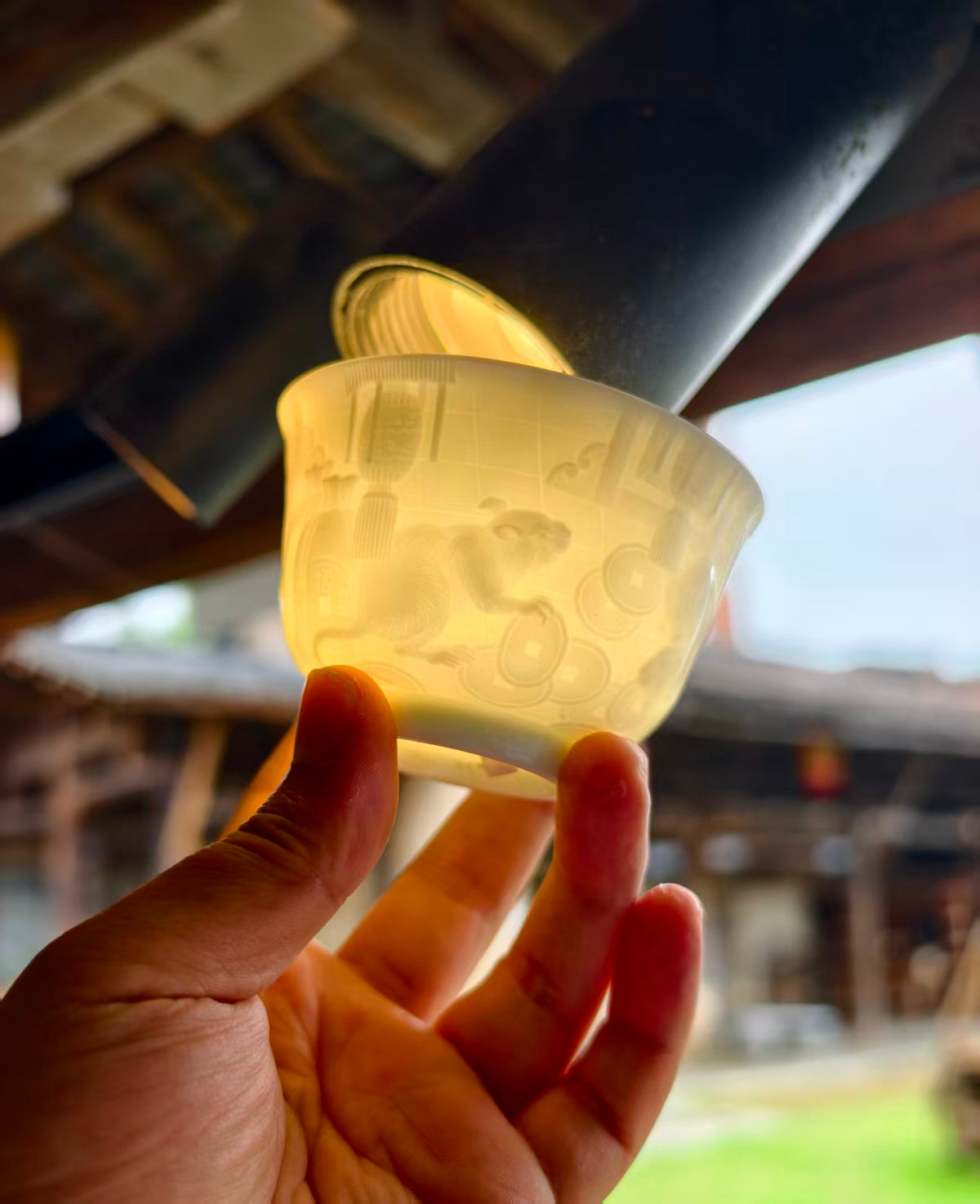 Hand-carved Rat Chinese Zodiac porcelain tea cup by Yan Wenlu shown under light
