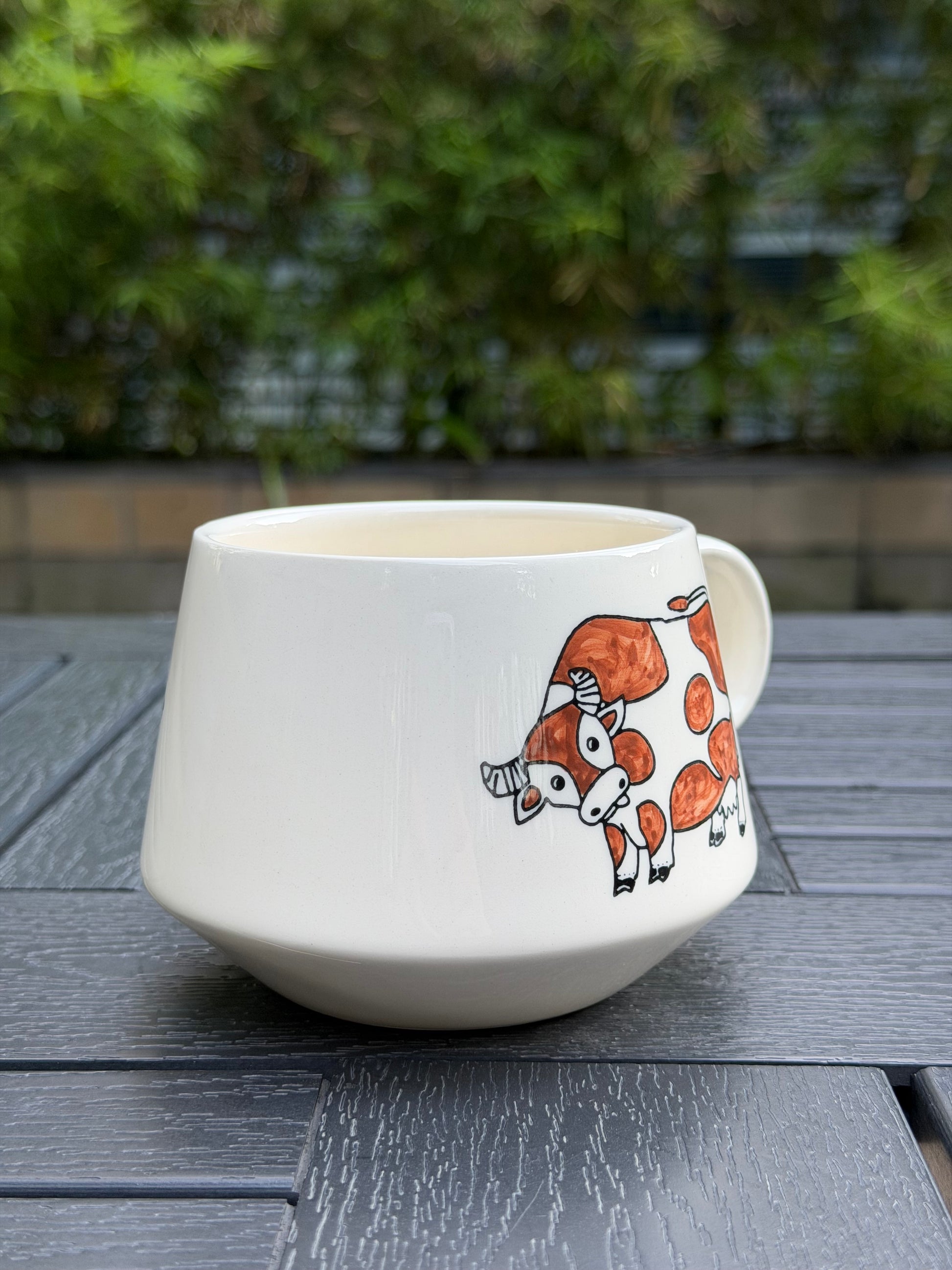 Angled view of Meadow Cow ceramic mug highlighting the hand-painted brown cow illustration