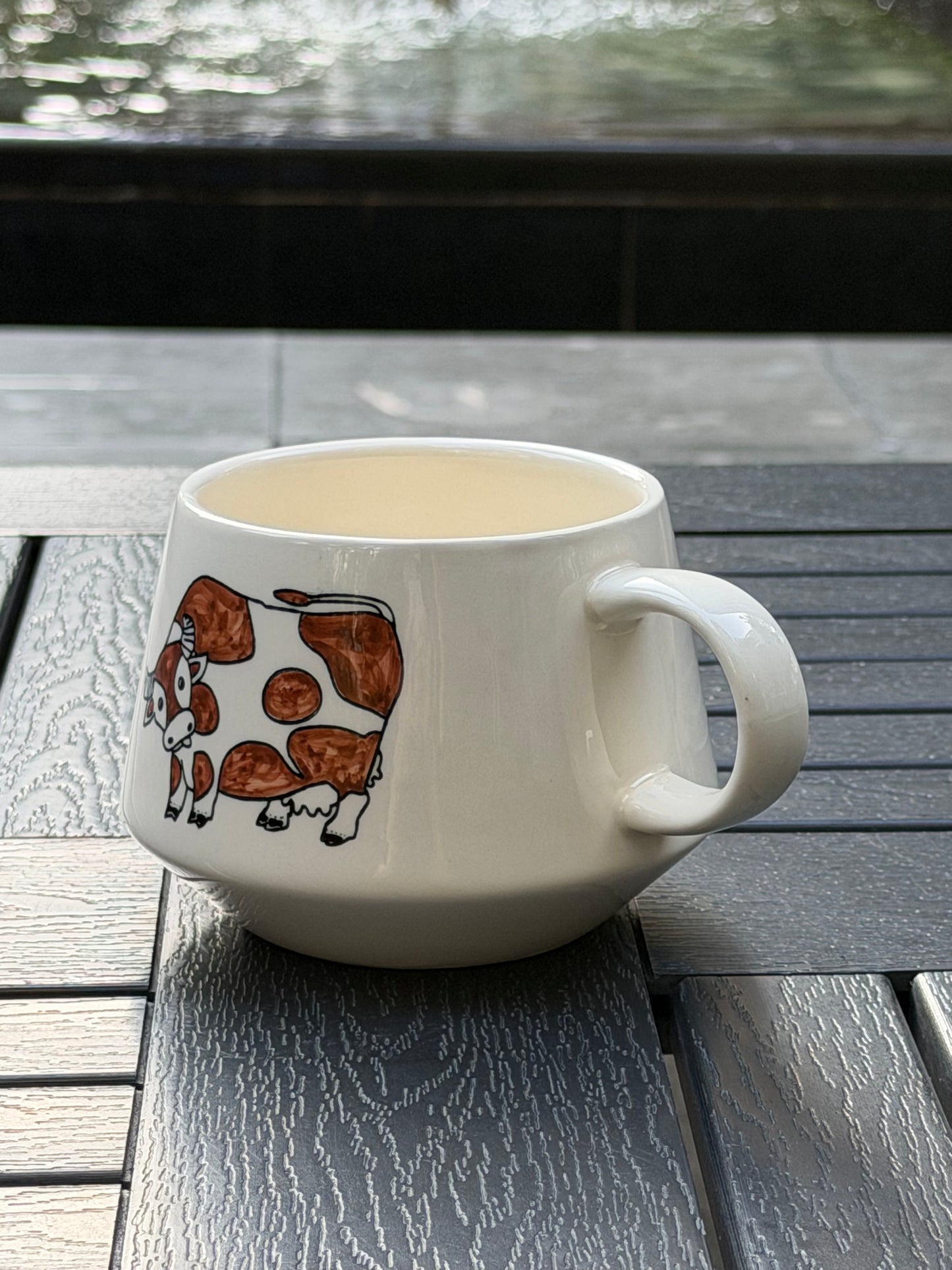 Side profile of Meadow Cow hand-painted ceramic mug with cow motif and rounded handle