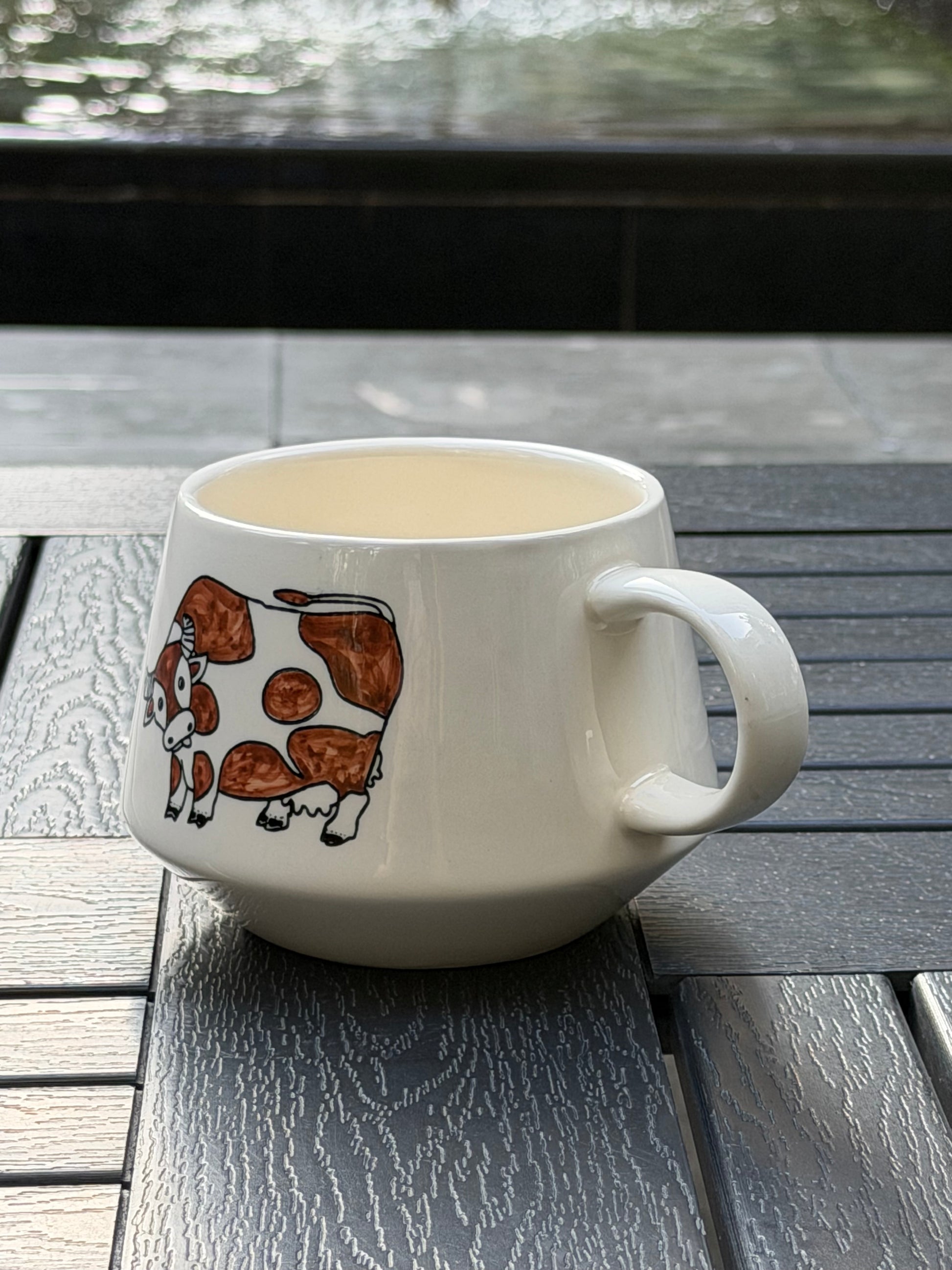 Side profile of Meadow Cow hand-painted ceramic mug with cow motif and rounded handle
