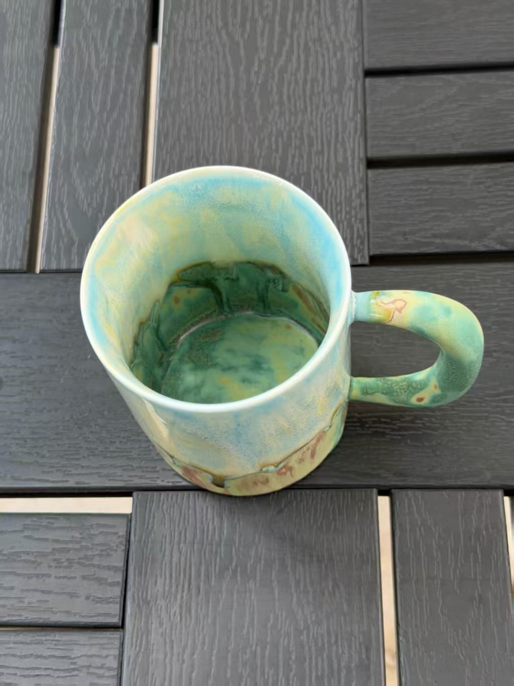 View into the mug showing pale blue inner walls transitioning to a deeper green glaze at the bottom.