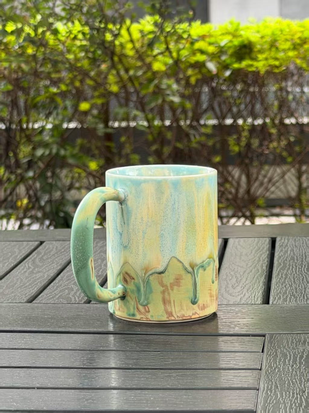 Side view with the handle on the left, showing the green handle glaze and raised flow pattern near the base.