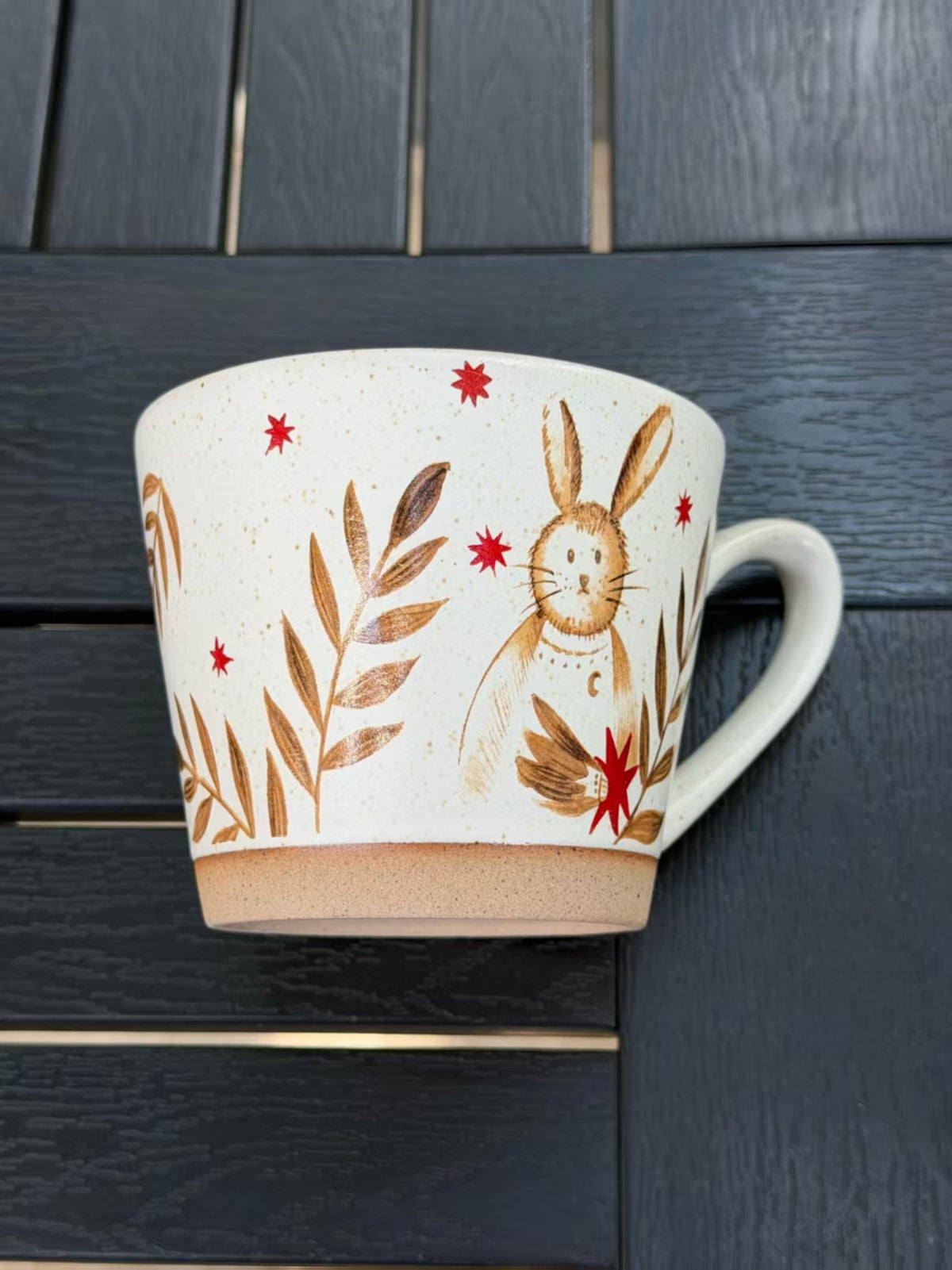 Close view of the Moonlit Rabbit ceramic mug showing its warm speckled glaze and rabbit botanical design