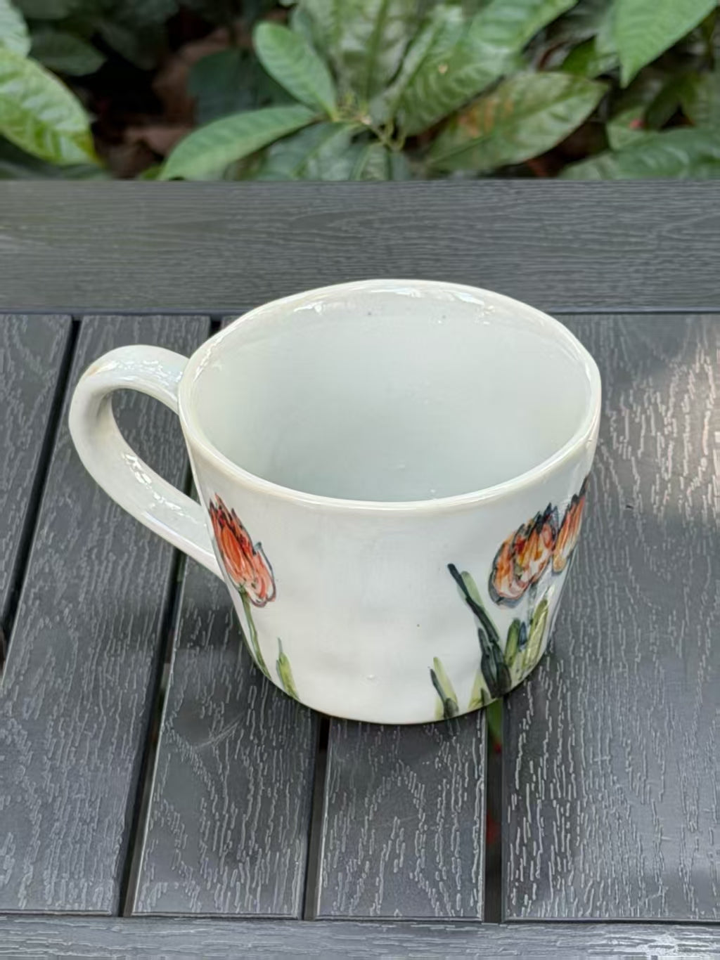 Angled top view of Orange Tulip stoneware mug showing glazed interior and hand-painted flowers
