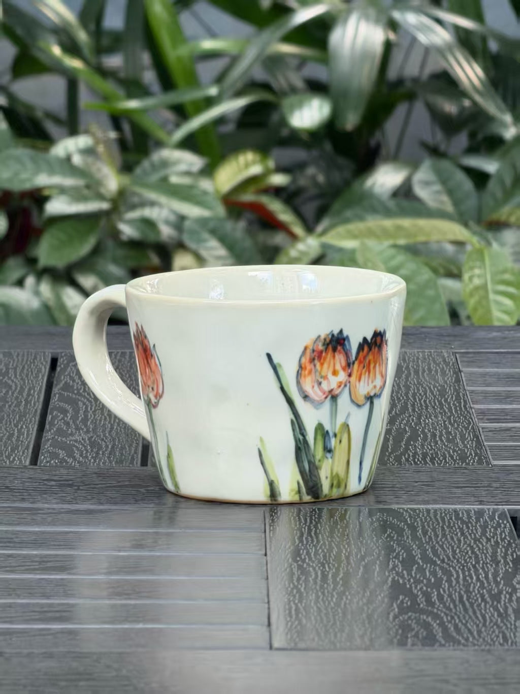 Side view of Orange Tulip stoneware mug with curved handle and freehand floral painting