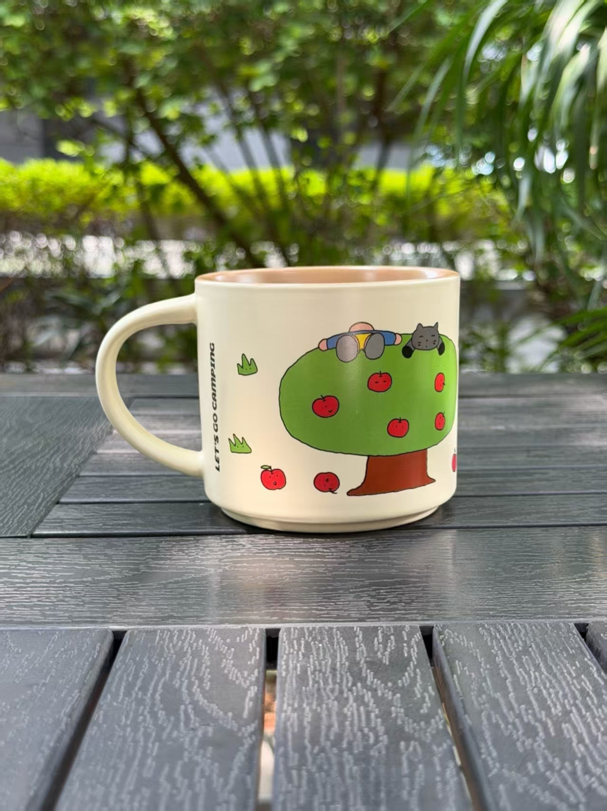 Reverse side of the Warm Sand ceramic mug featuring a green apple tree with red fruit.