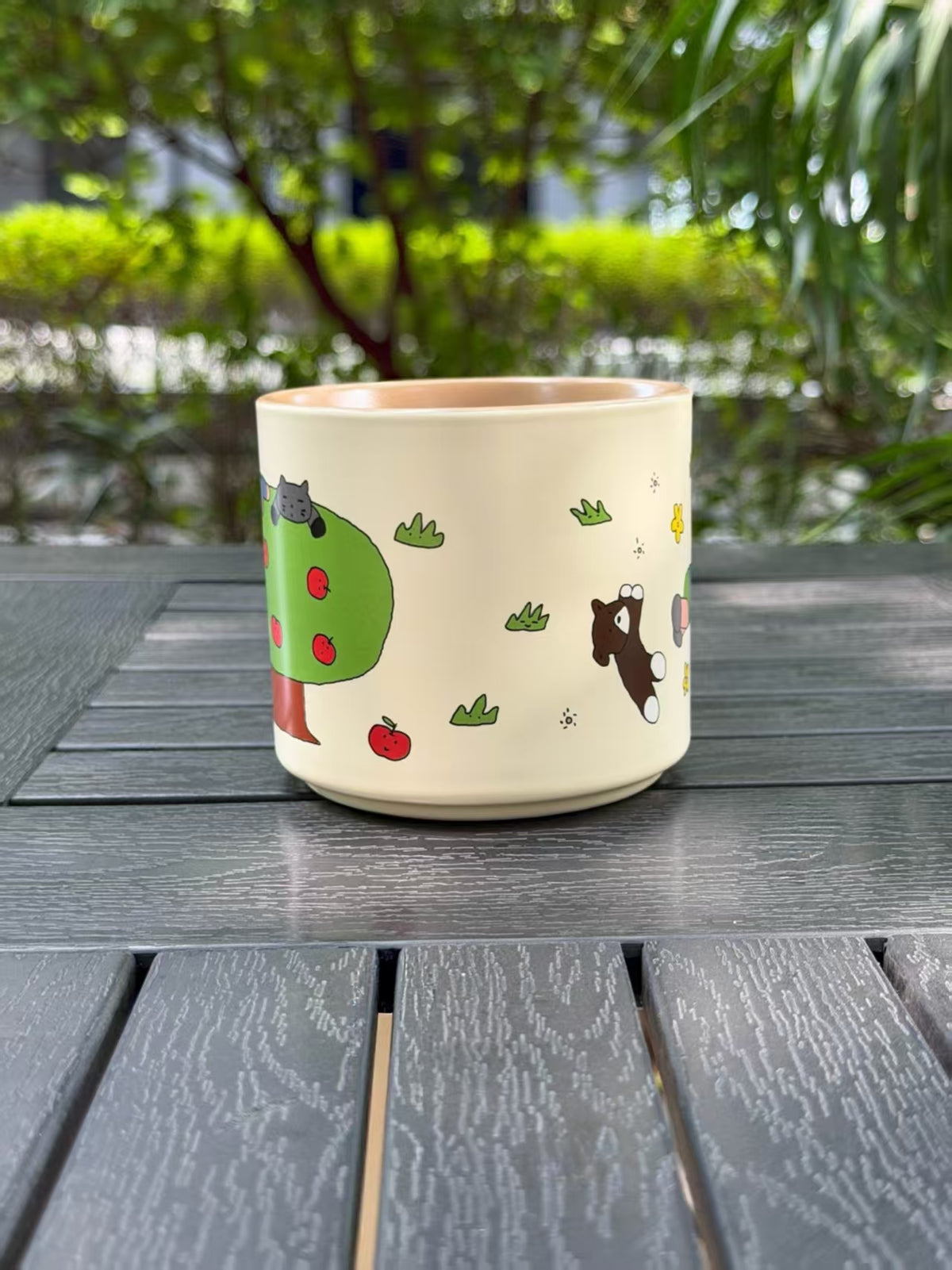 Side view of the Warm Sand mug showing how the apple tree and animal illustrations continue around the cup.