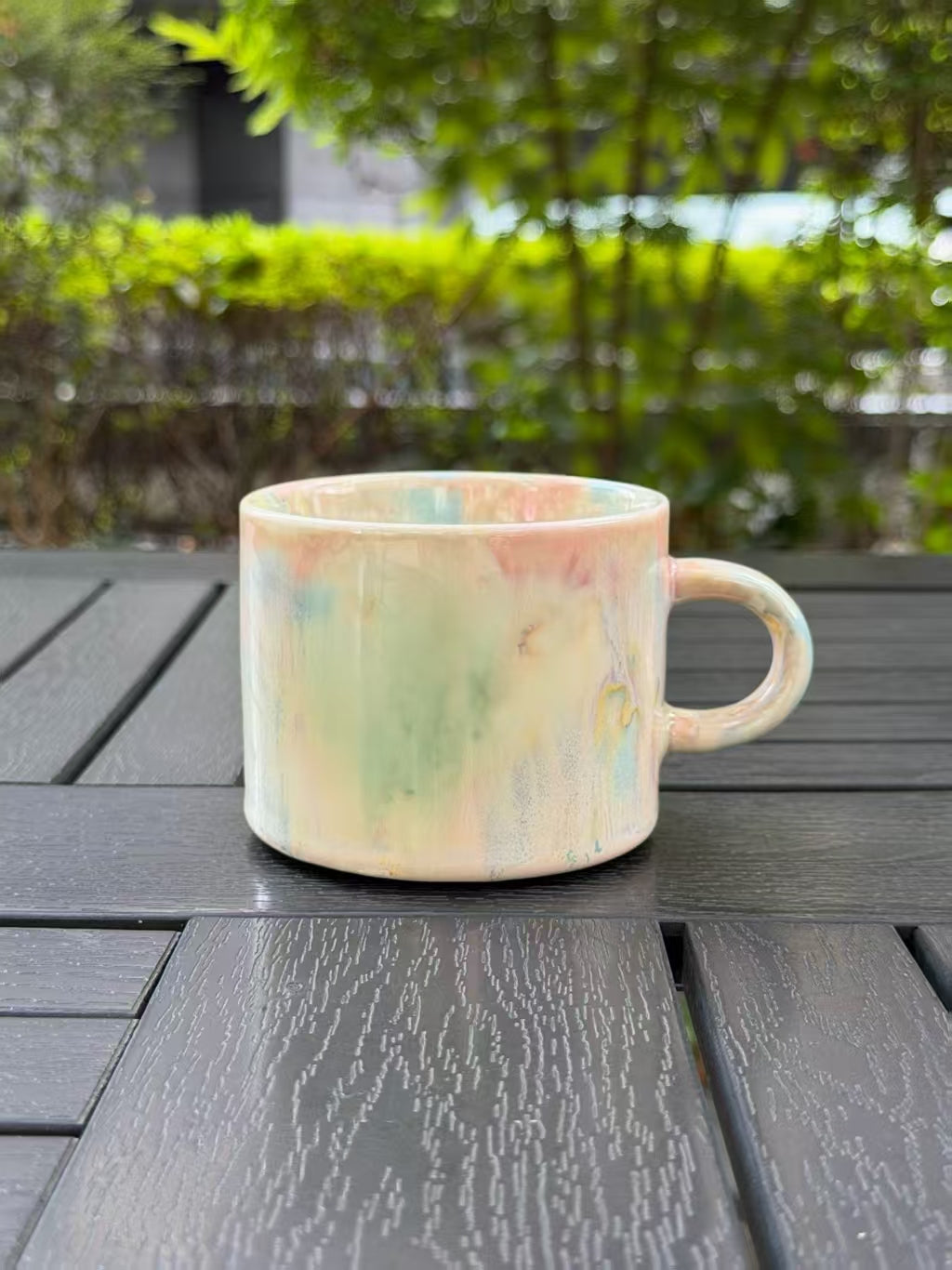 Full view of the Pastel Meadow mug on a dark outdoor table, with its handle on the right