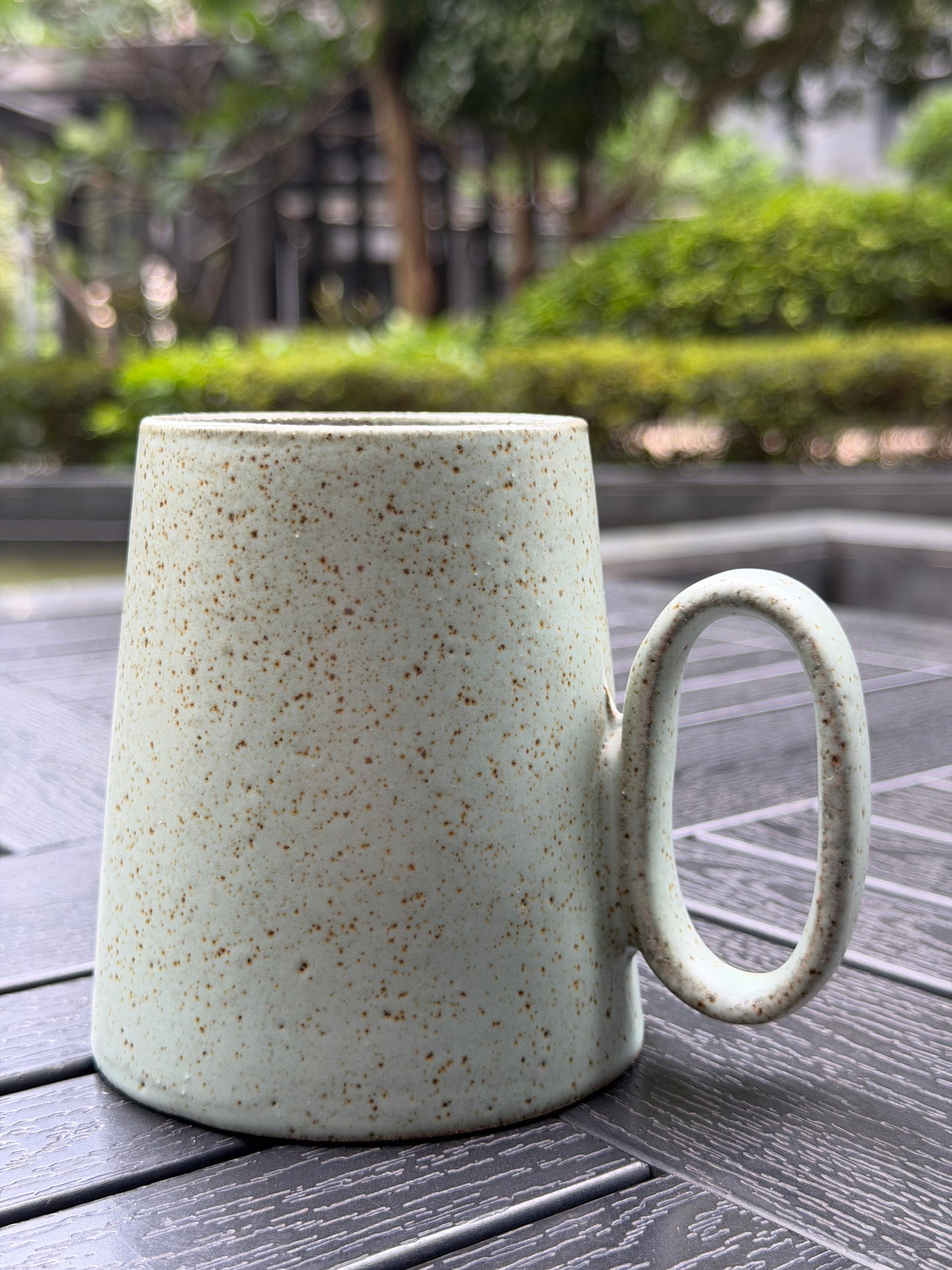 Quiet Meadow Mug – back view showing wide-base tapered silhouette and speckled sage green glaze