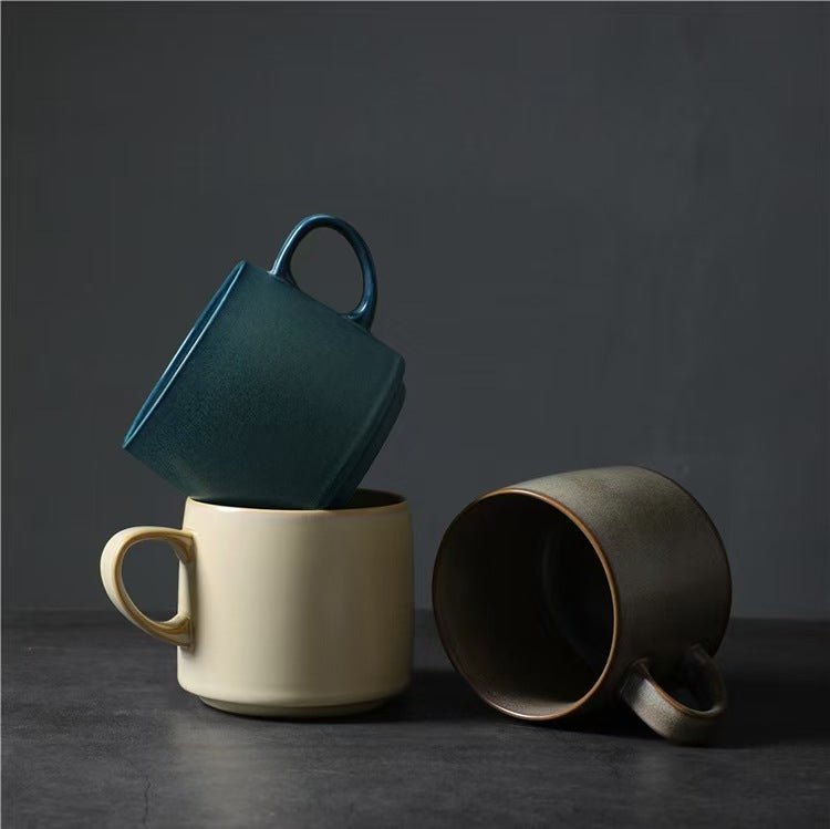 Three Quiet Tones ceramic mugs in Deep Teal, Soft Almond and Warm Stone arranged in a stacked studio display