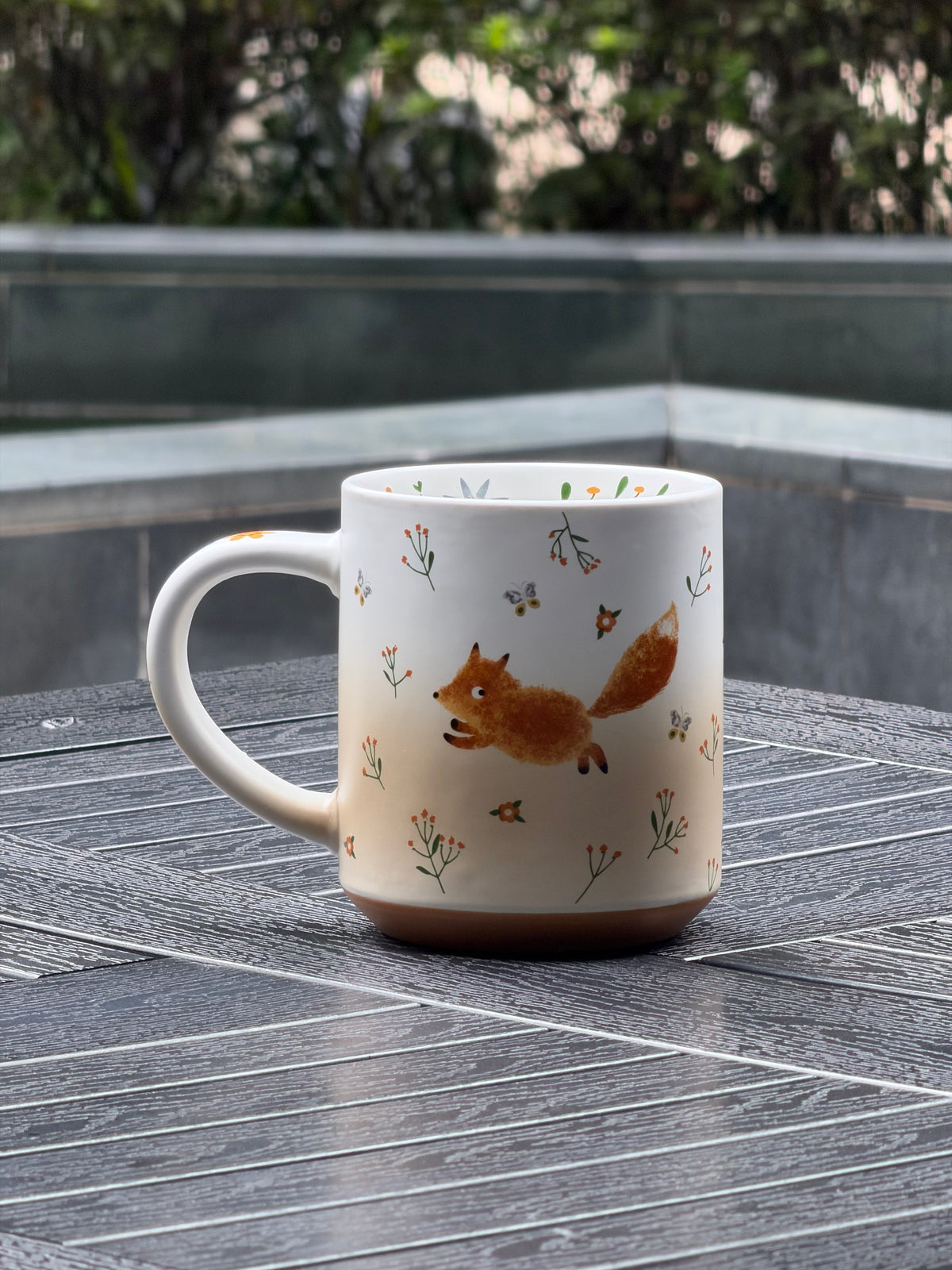 Matte ceramic mug featuring a running fox among small wildflowers and bees
