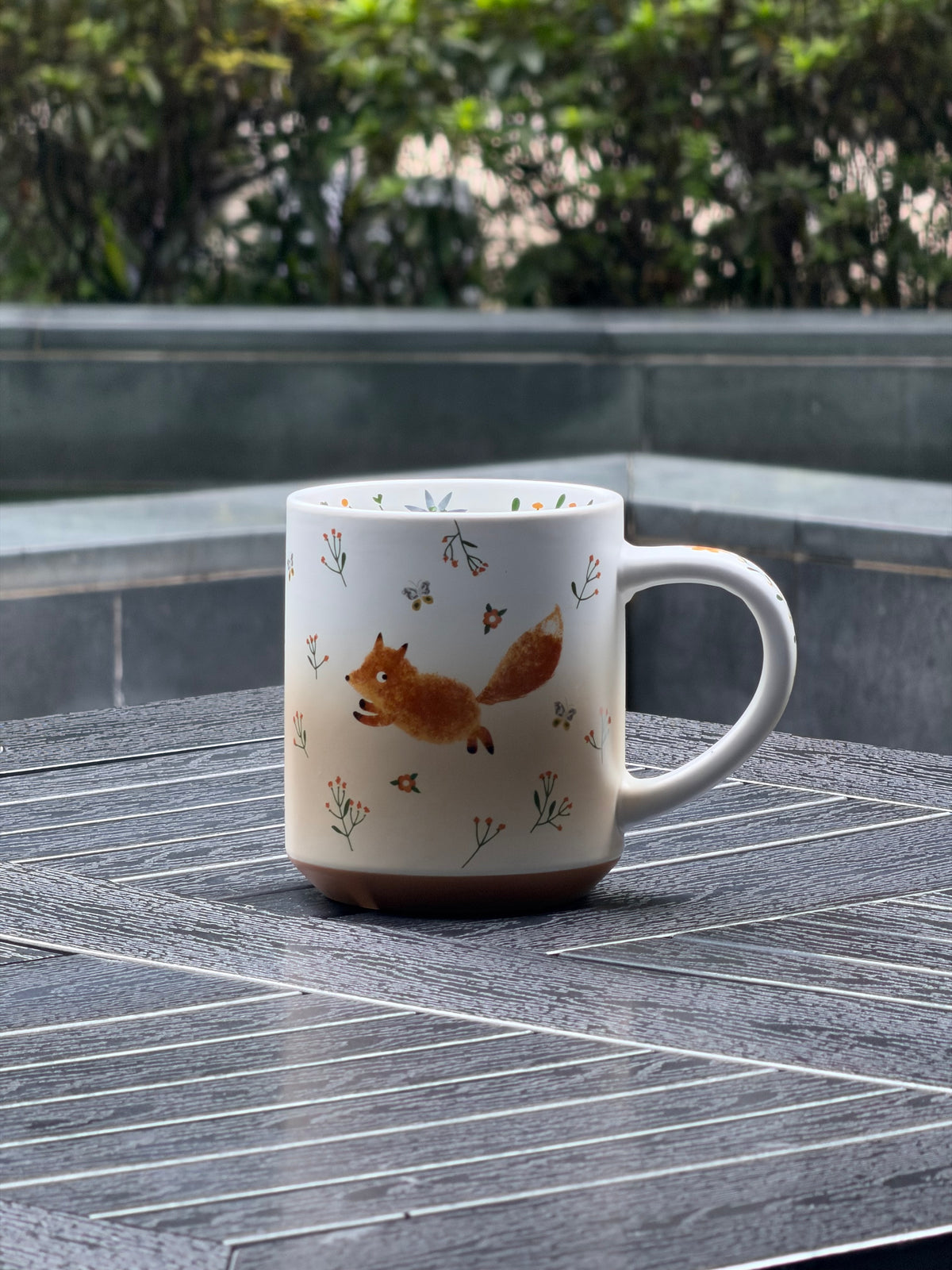 Front view of large matte ceramic mug with running fox, wildflowers and curved handle