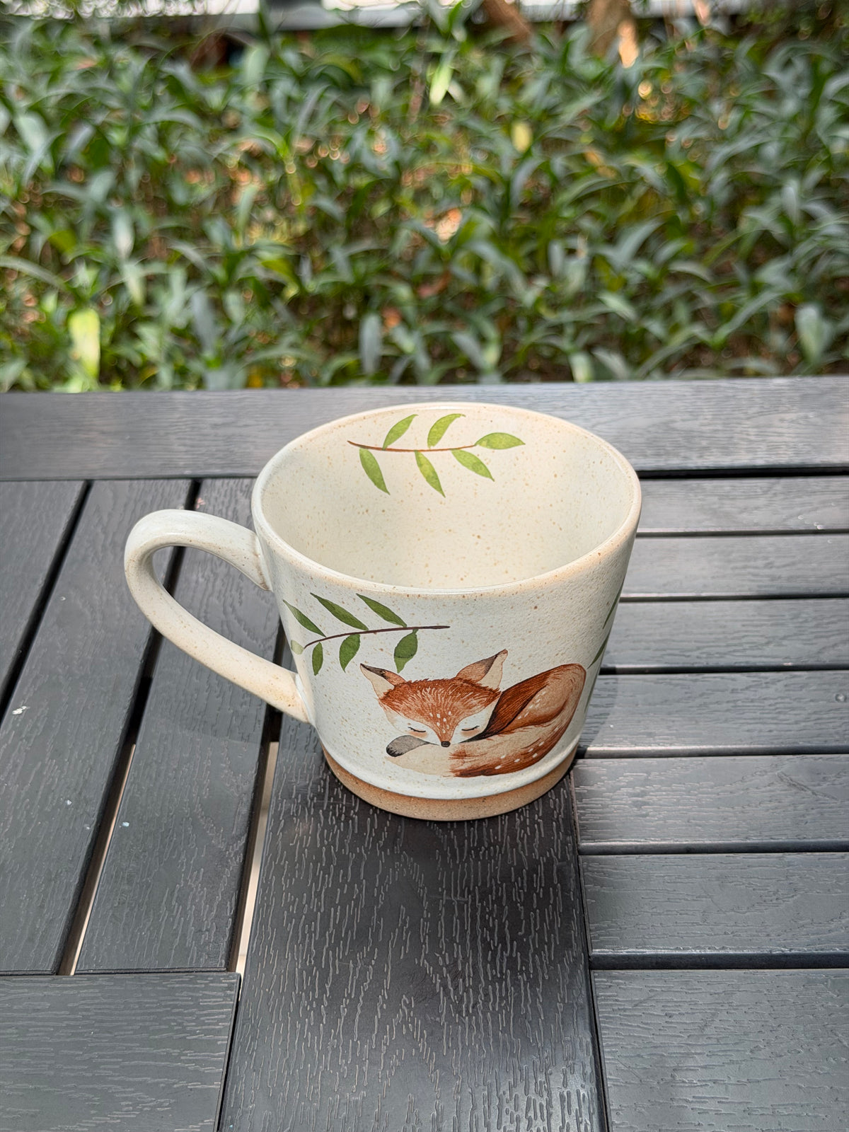 Angled overhead view of the sleeping fox mug showing the illustration, rim and interior leaves