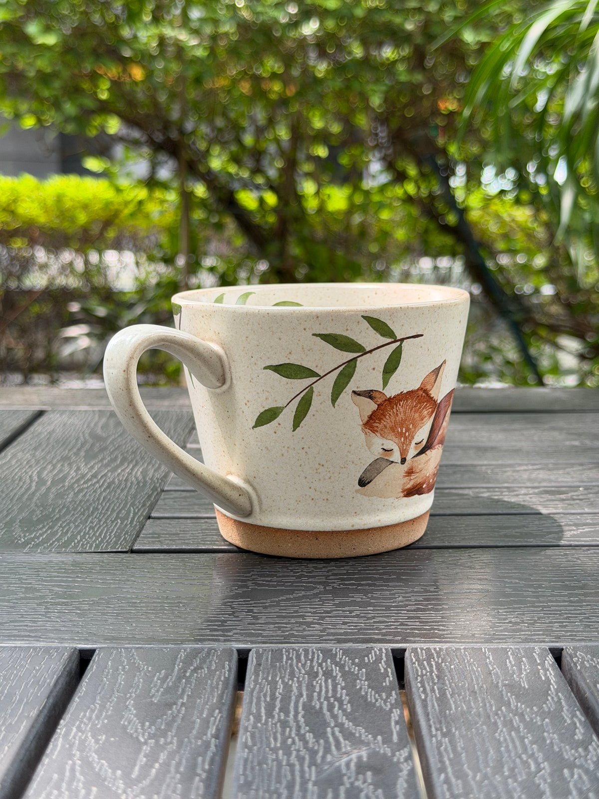 Angled view of the mug handle and leafy design, with part of the fox visible