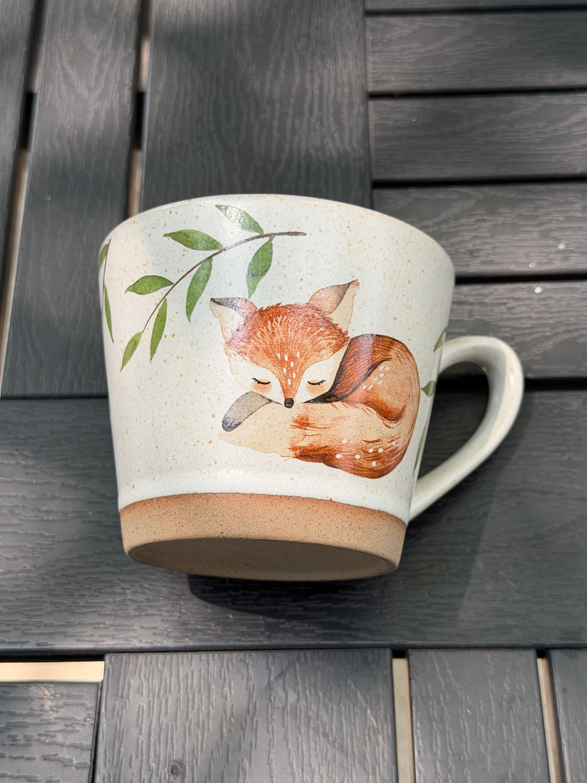 Mug laid on its side for a closer look at the sleeping fox and unglazed base ring