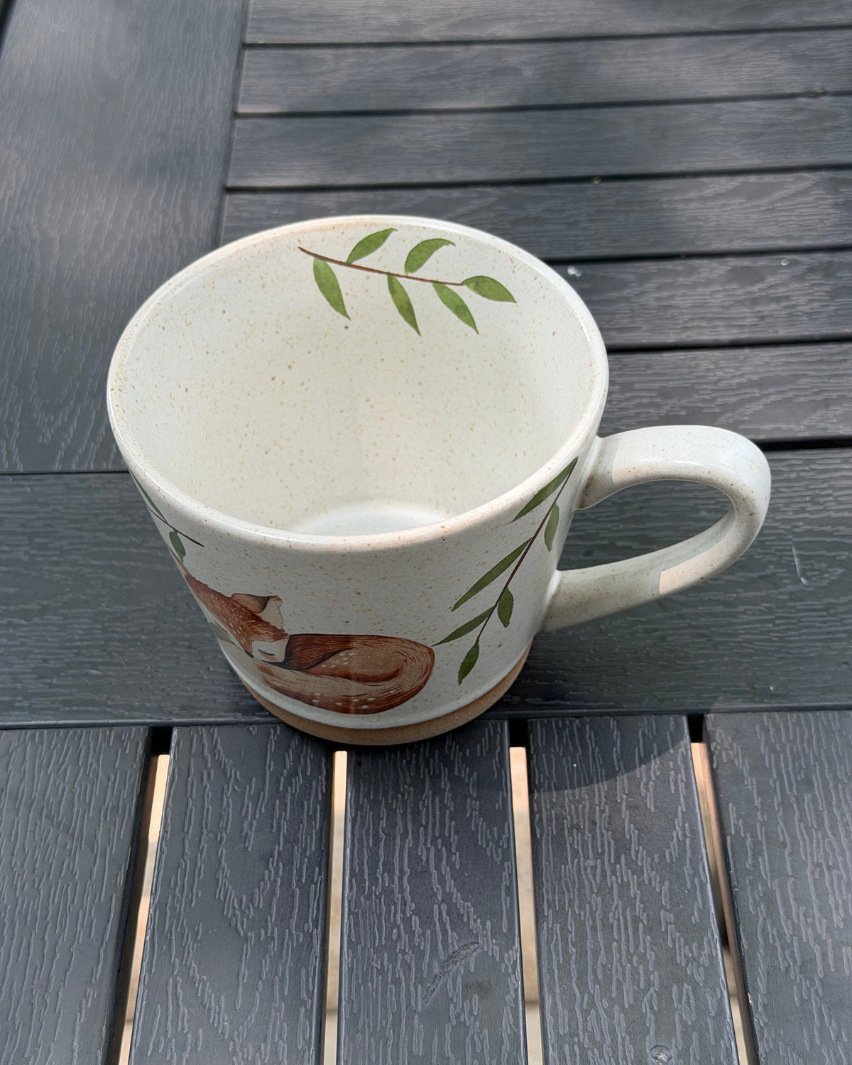 Overhead view of the mug showing its cream interior, green leaves and fox illustration outside