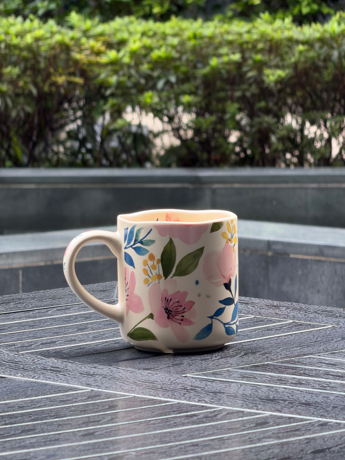 Back view of Soft Bloom ceramic mug with a wraparound pink, blue, green, and yellow floral pattern