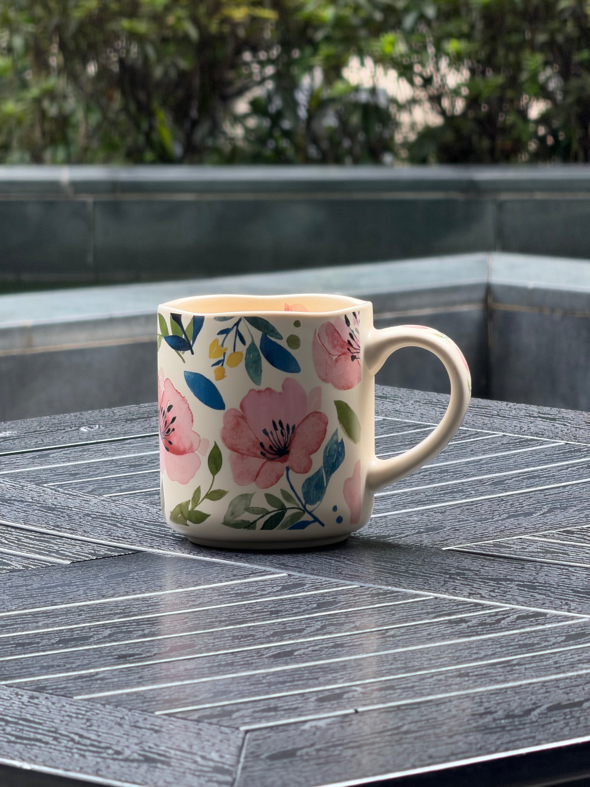 Matte floral ceramic mug with soft pink blooms, leafy details, and an irregular wavy rim