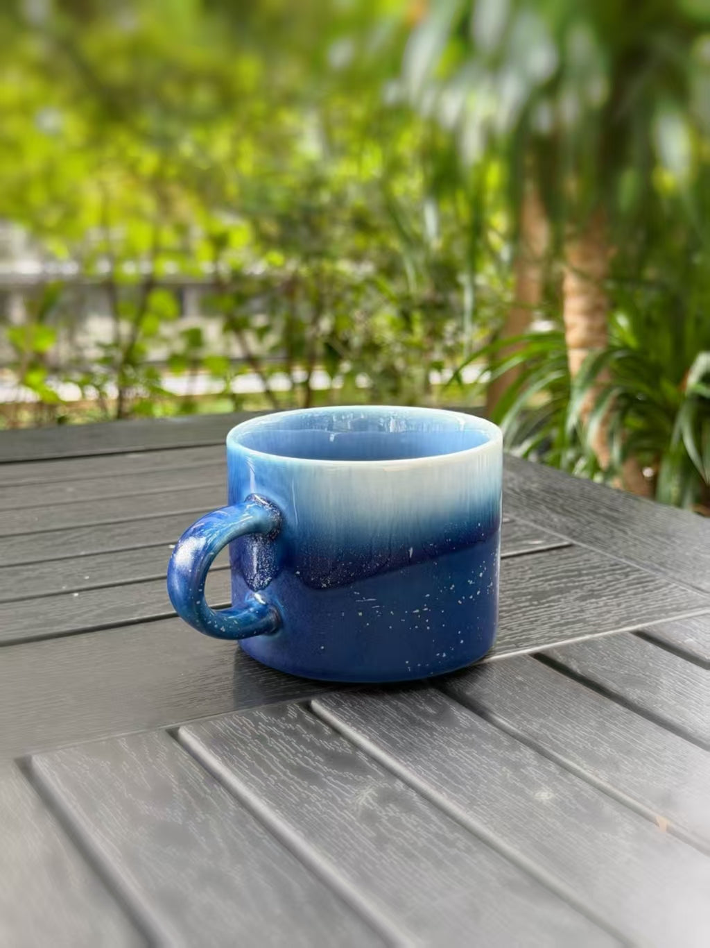Angled view of the mug showing its blue handle, open rim and curved body