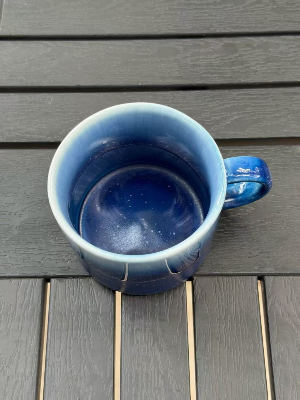 Overhead view into the mug showing its deep blue glazed interior, rounded base and handle