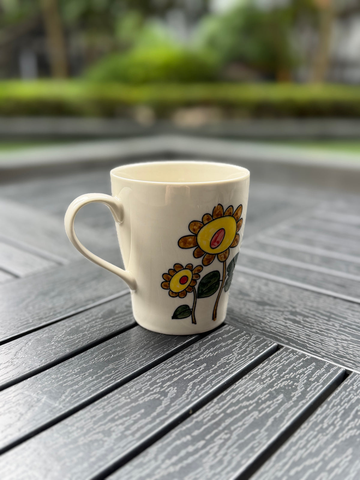 Side view of the Sunflower Muse hand-painted ceramic mug with yellow sunflowers, an ivory glaze and a curved handle.