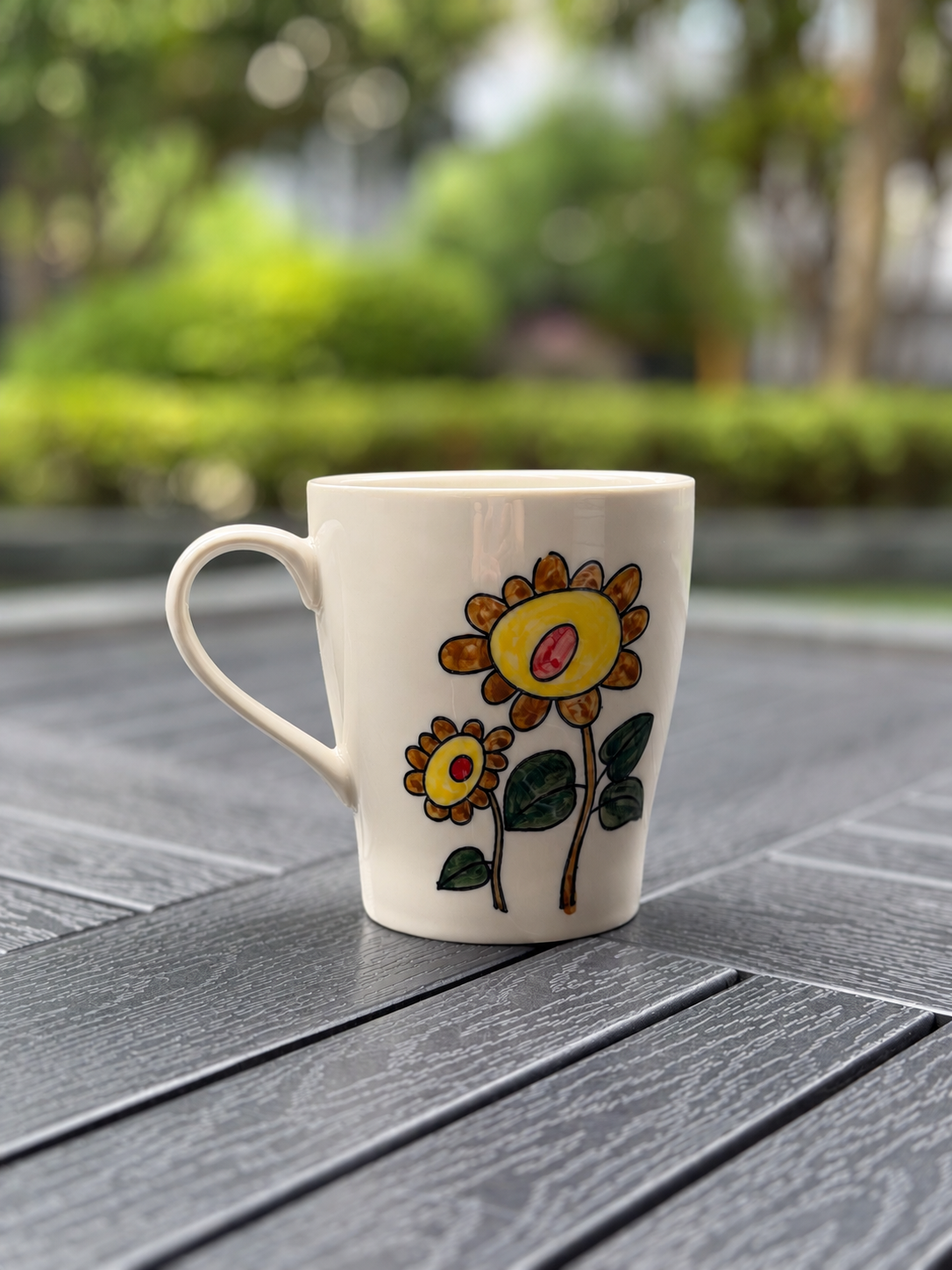 Close angled view of the Sunflower Muse ceramic mug showing hand-painted yellow sunflowers on an ivory glaze.