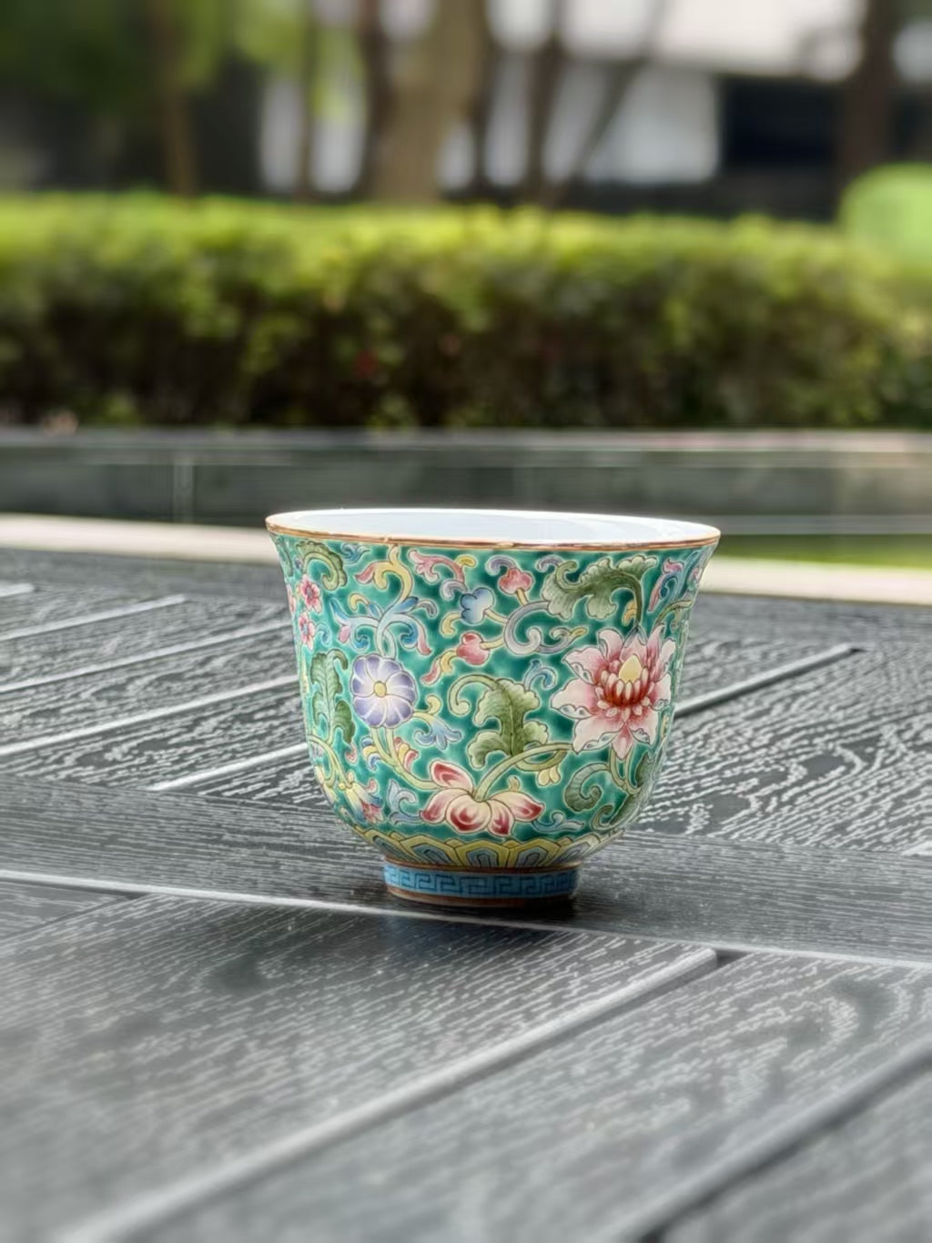 Front view of the small porcelain teacup with pink blossoms and intricate green leaves