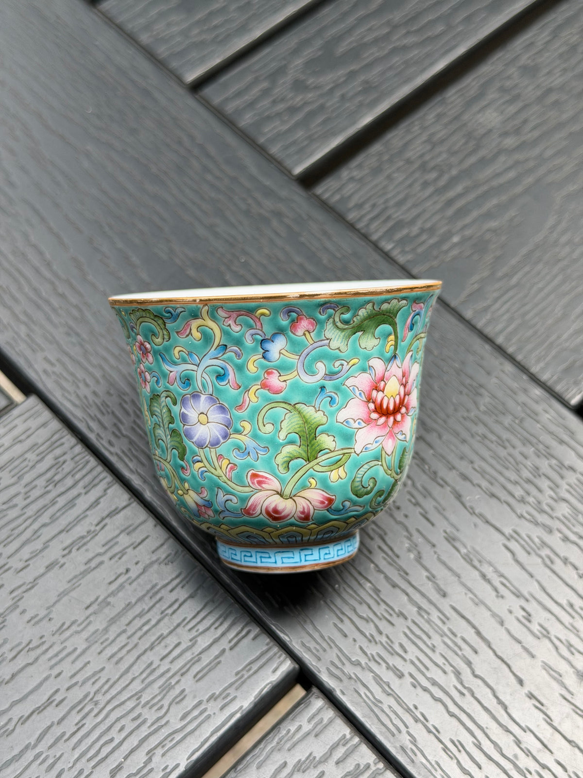 Porcelain teacup laid on its side, showing the floral exterior, rim and cup shape