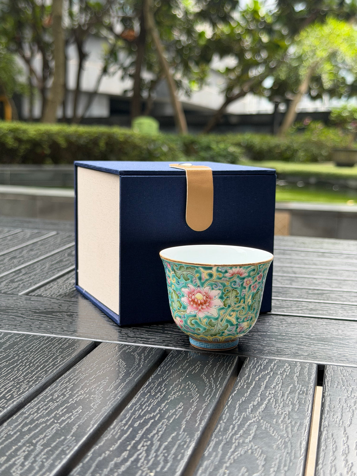 Ying Shengxiang floral teacup displayed beside its blue and cream gift box